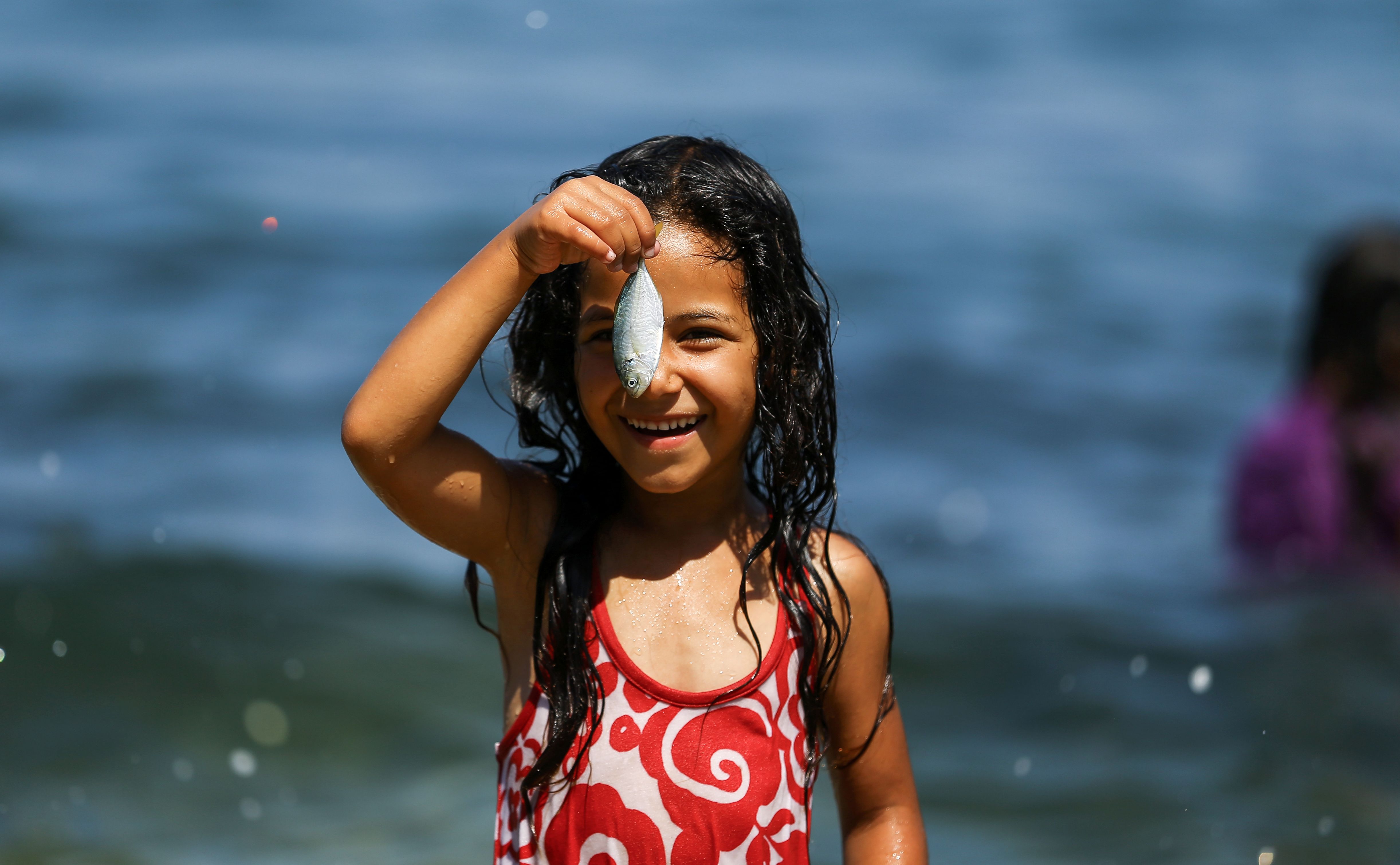 طفلة فلسطينية تمسك سمكة صغيرة