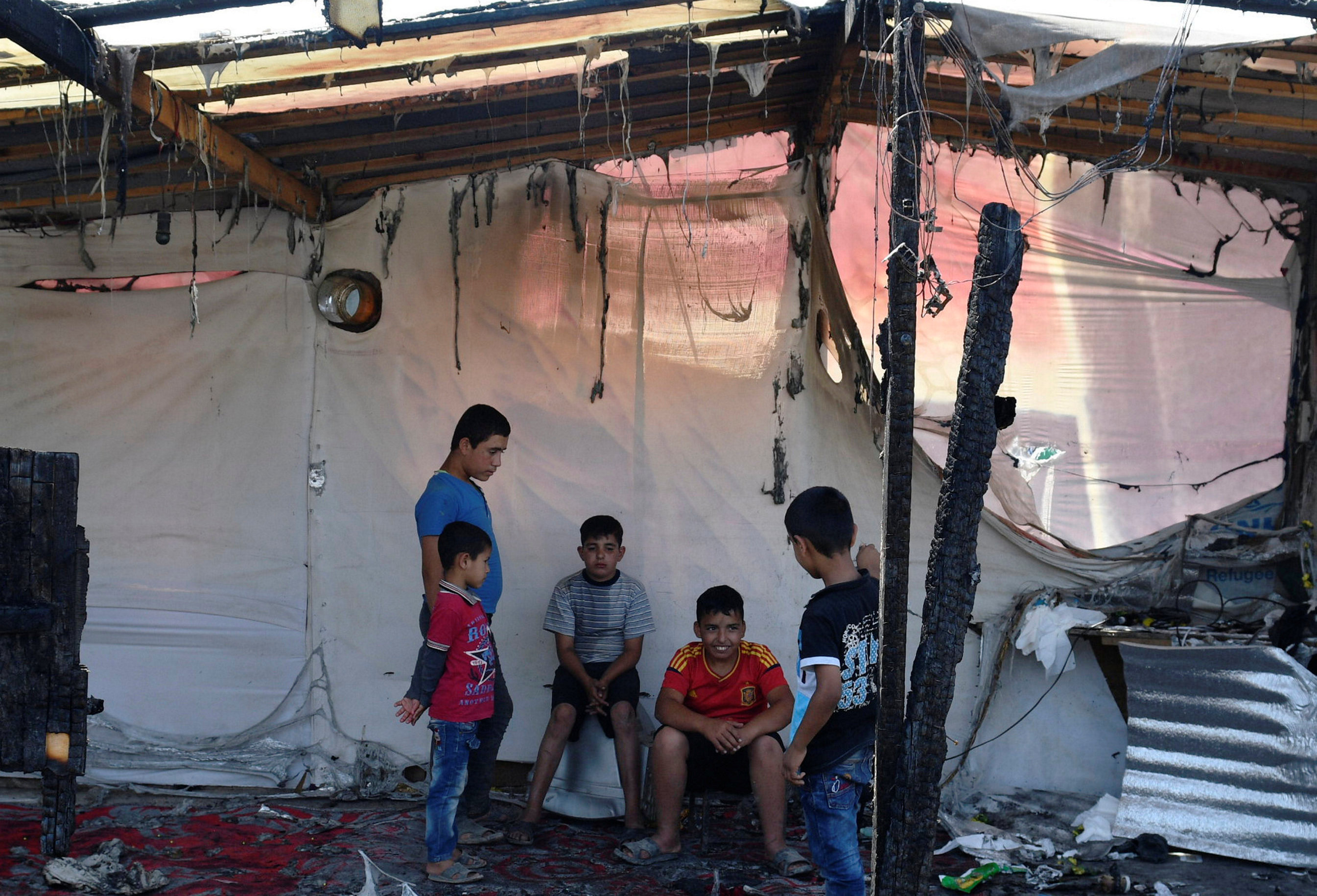 الإطفال يجلسون داخل حطام حريق المخيم فى لبنان
