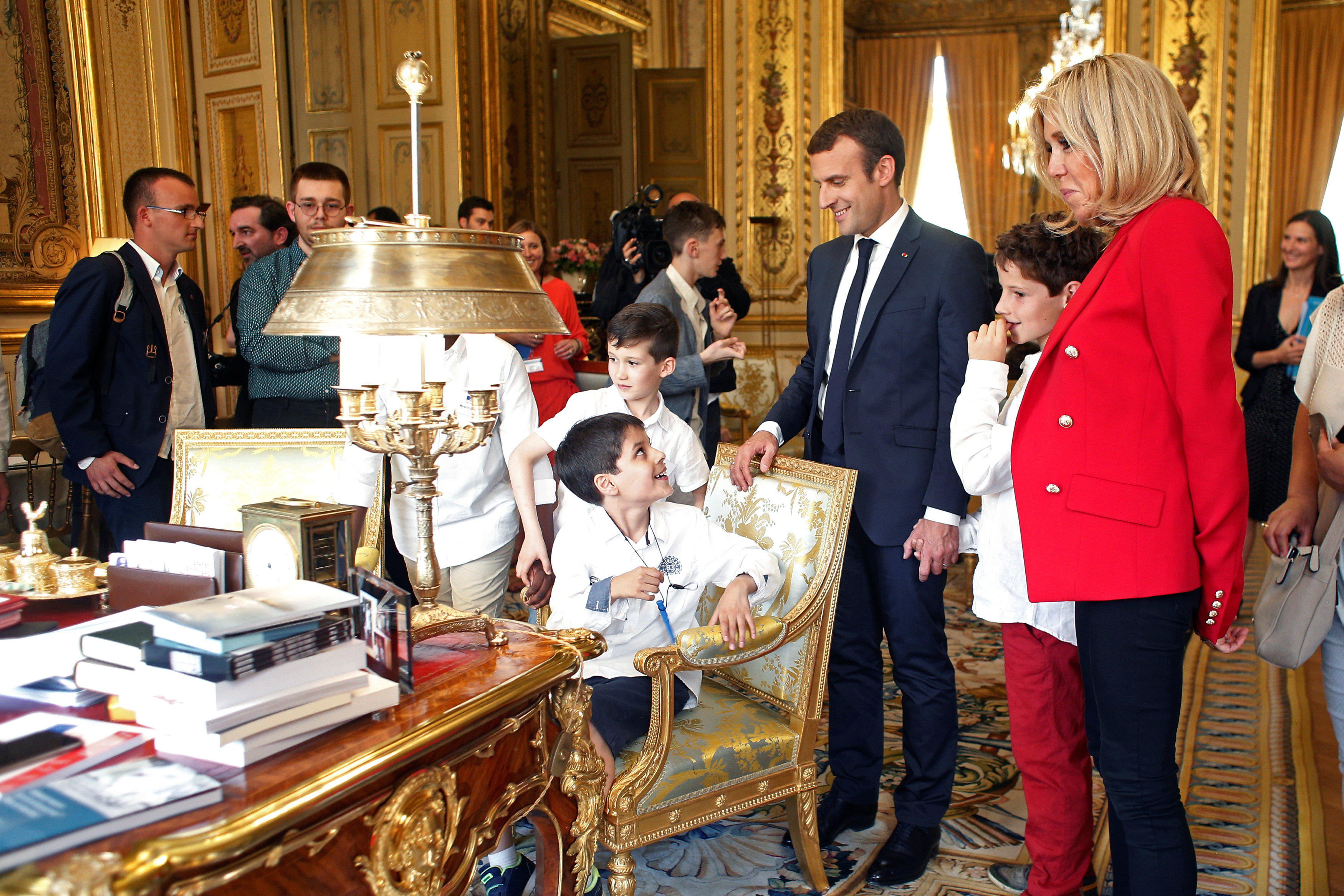 طفل يجلس أمام الرئيس الفرنسي وزوجته