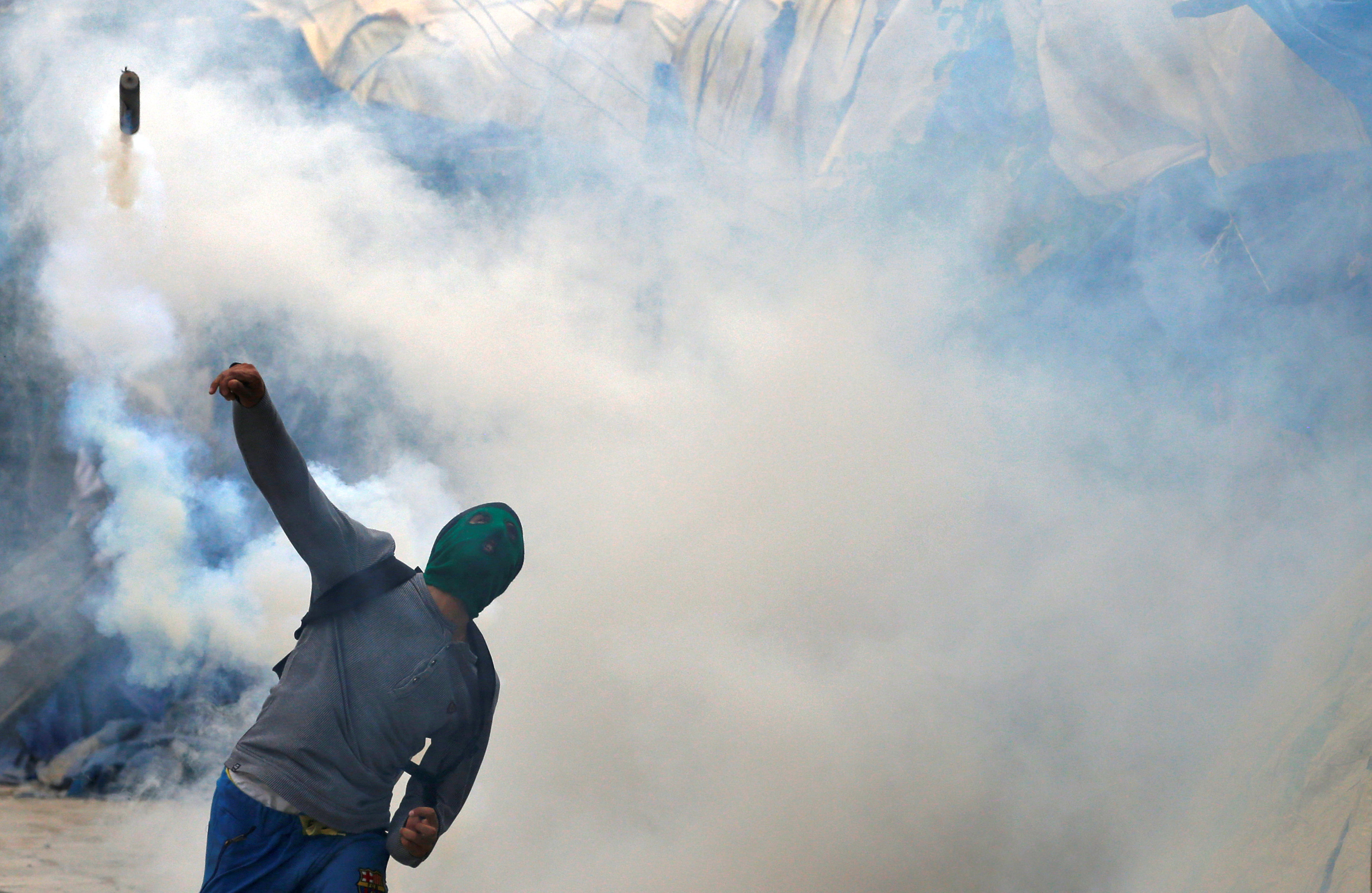 محتج يرد قنابل الغاز علي الشرطة