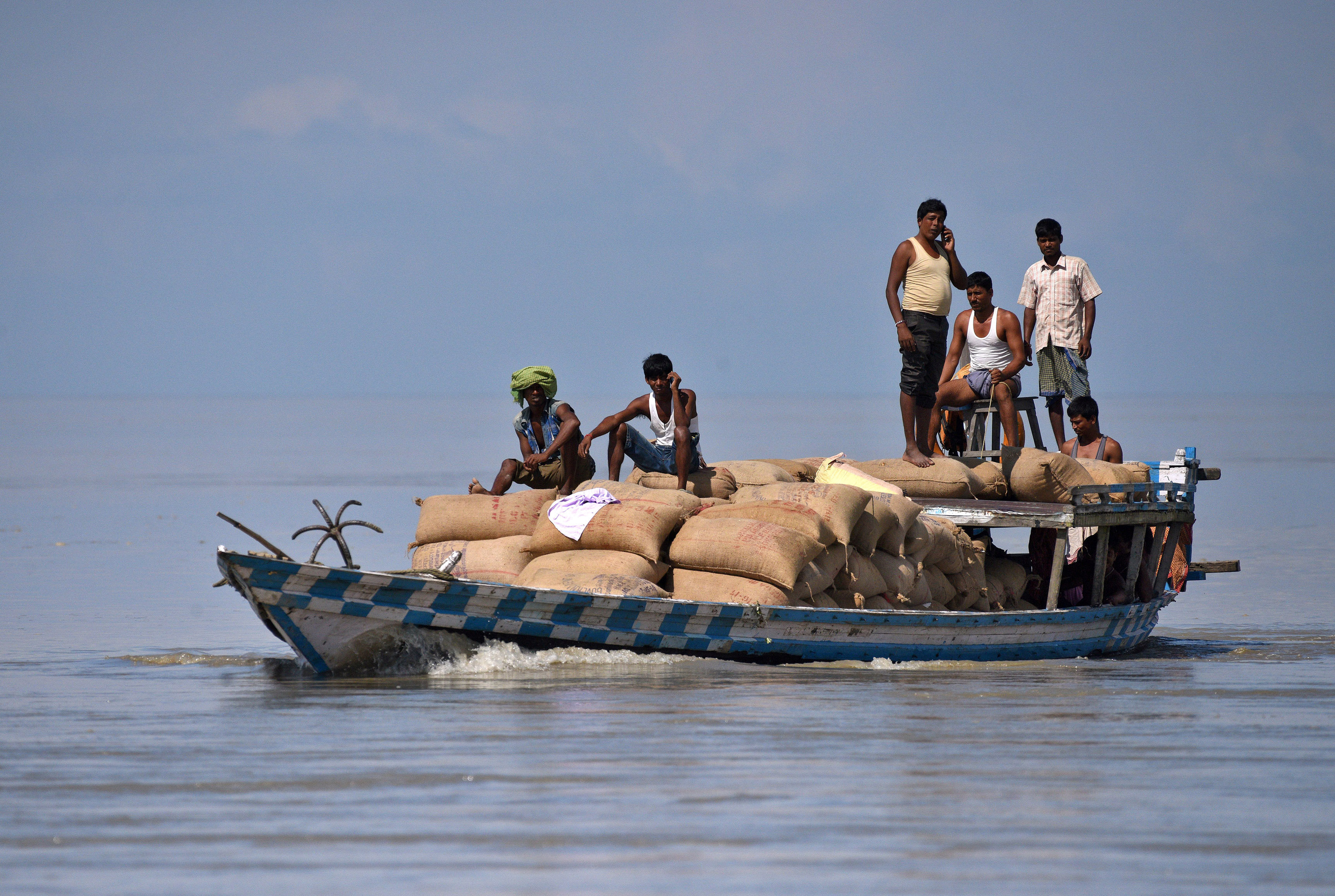 رجال ينقلون بضاعتهم بقارب صغير عبر مياه الفيضان فى الهند