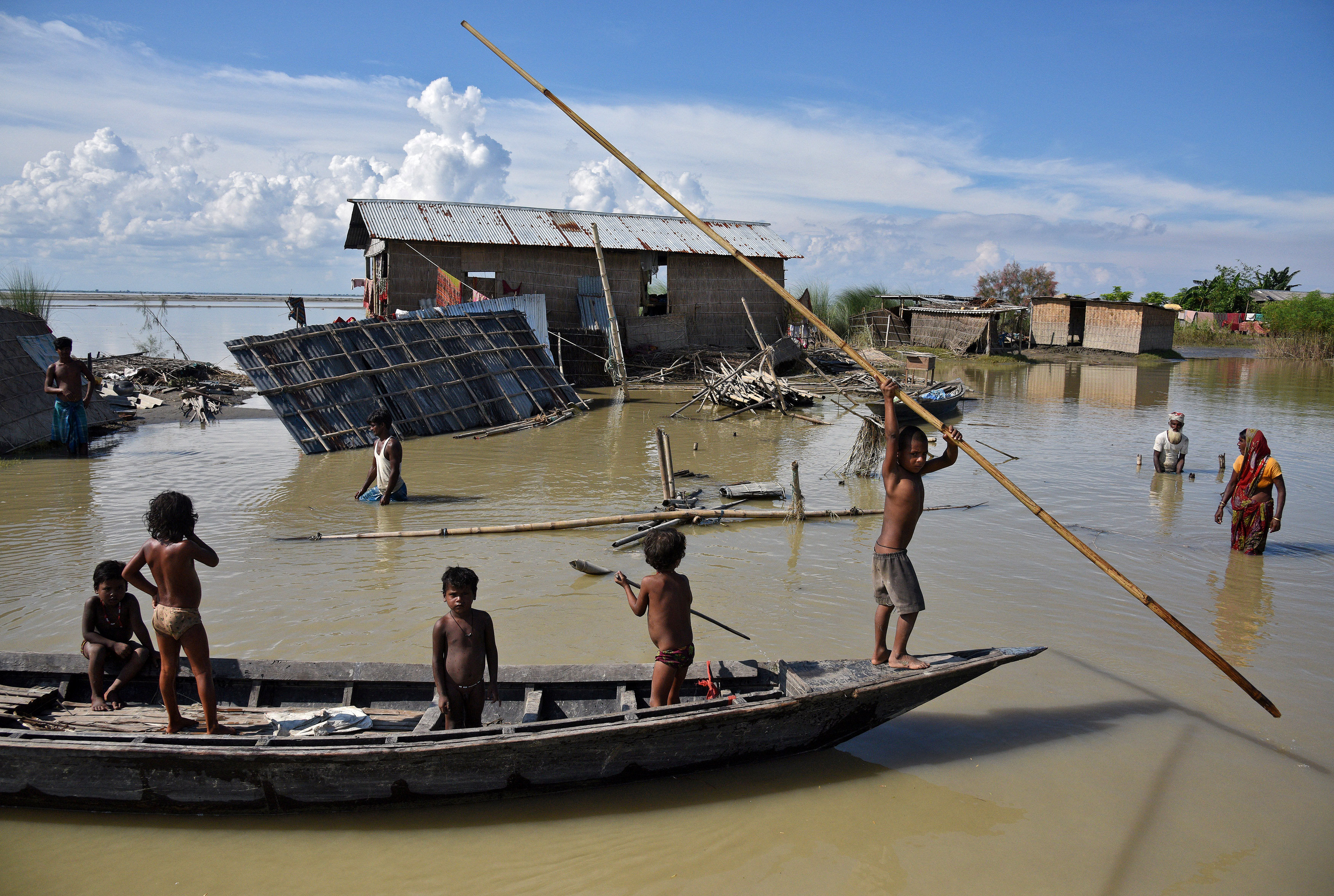 أطفال يستخدمون قارب صغير للتنقل وسط مياه الفيضان