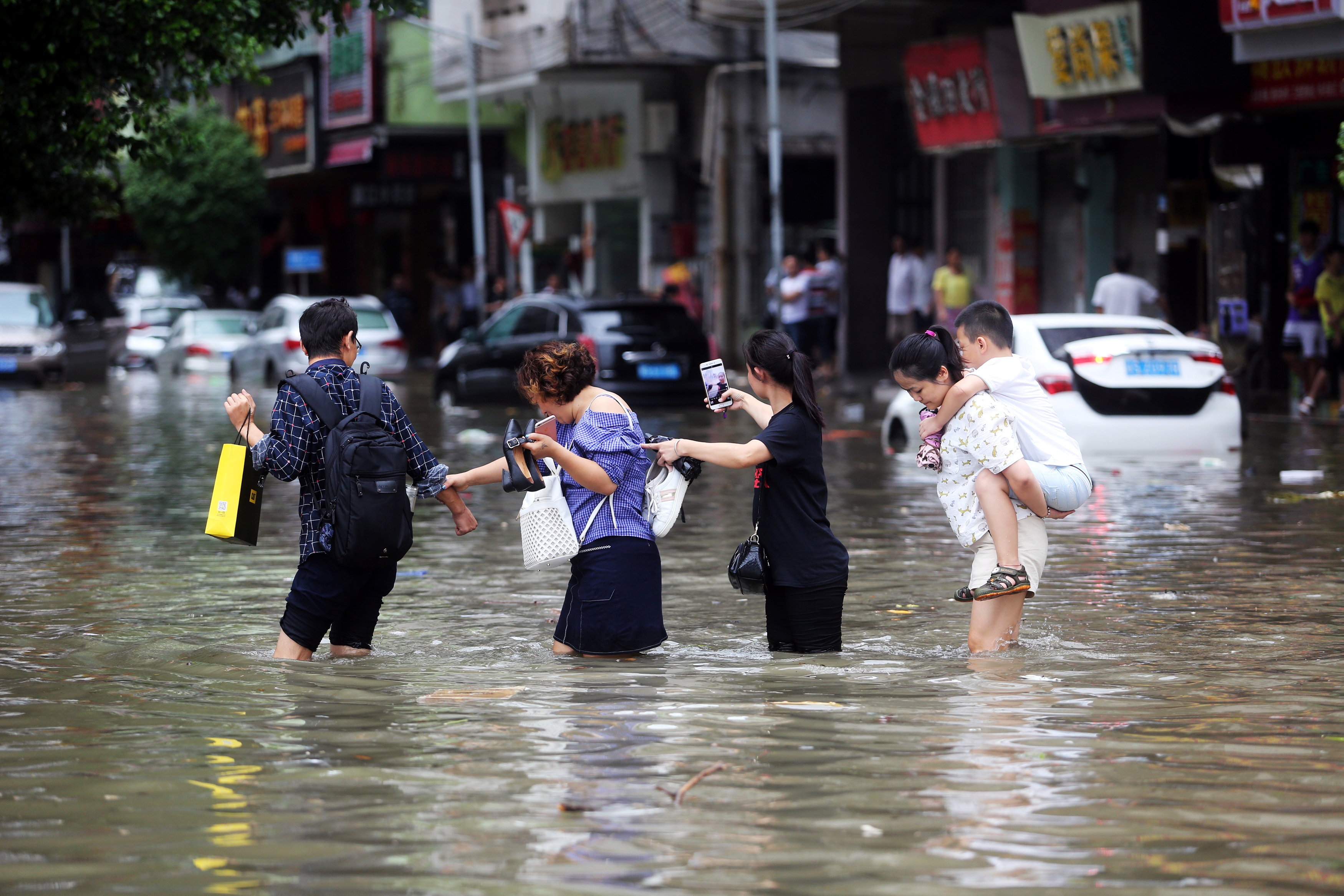 المواطنون يعبرون الشوارع وسط مياه الأمطار فى الصين