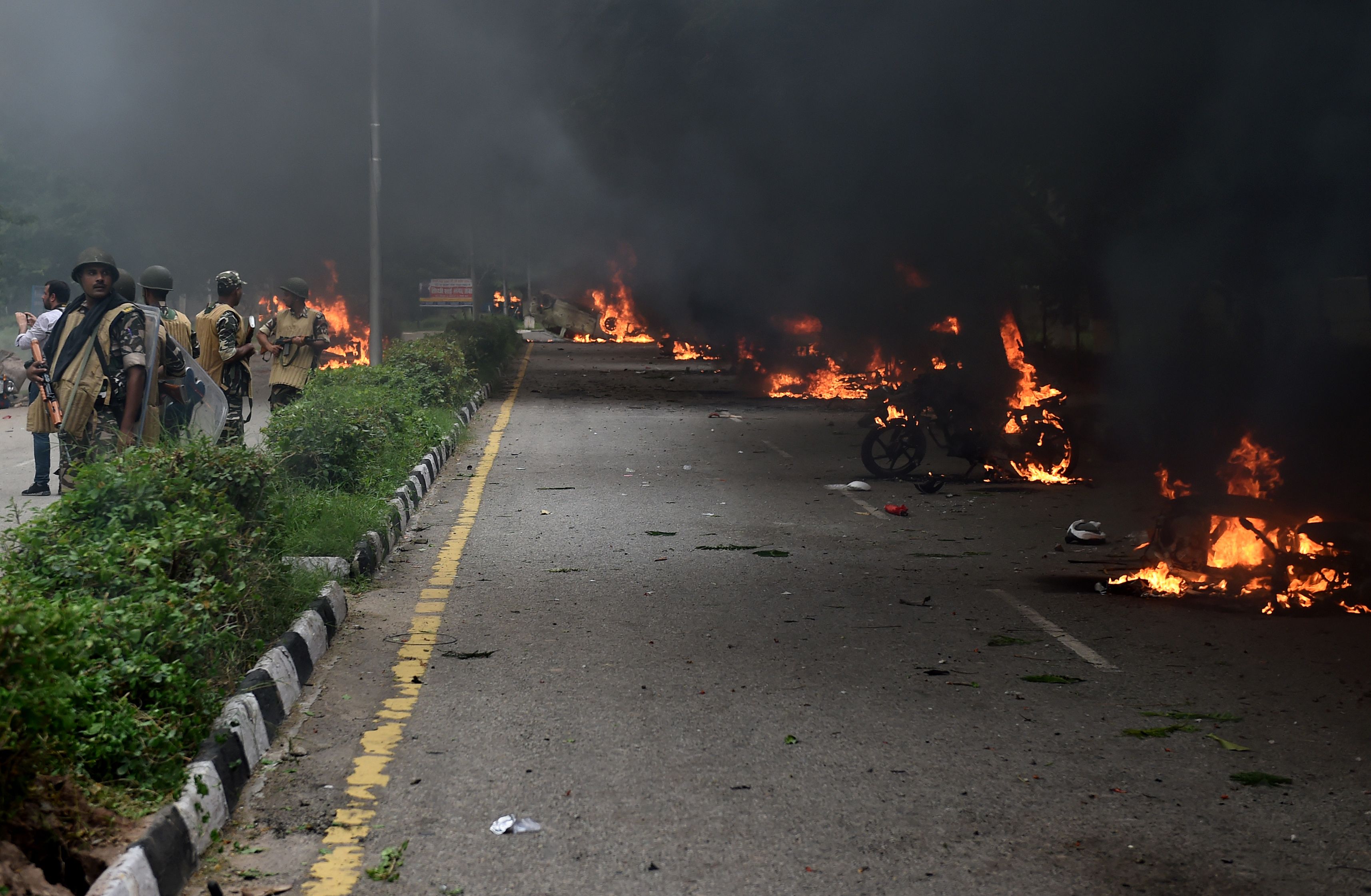 رجال الأمن الهنود قرب السيارات المحترقة