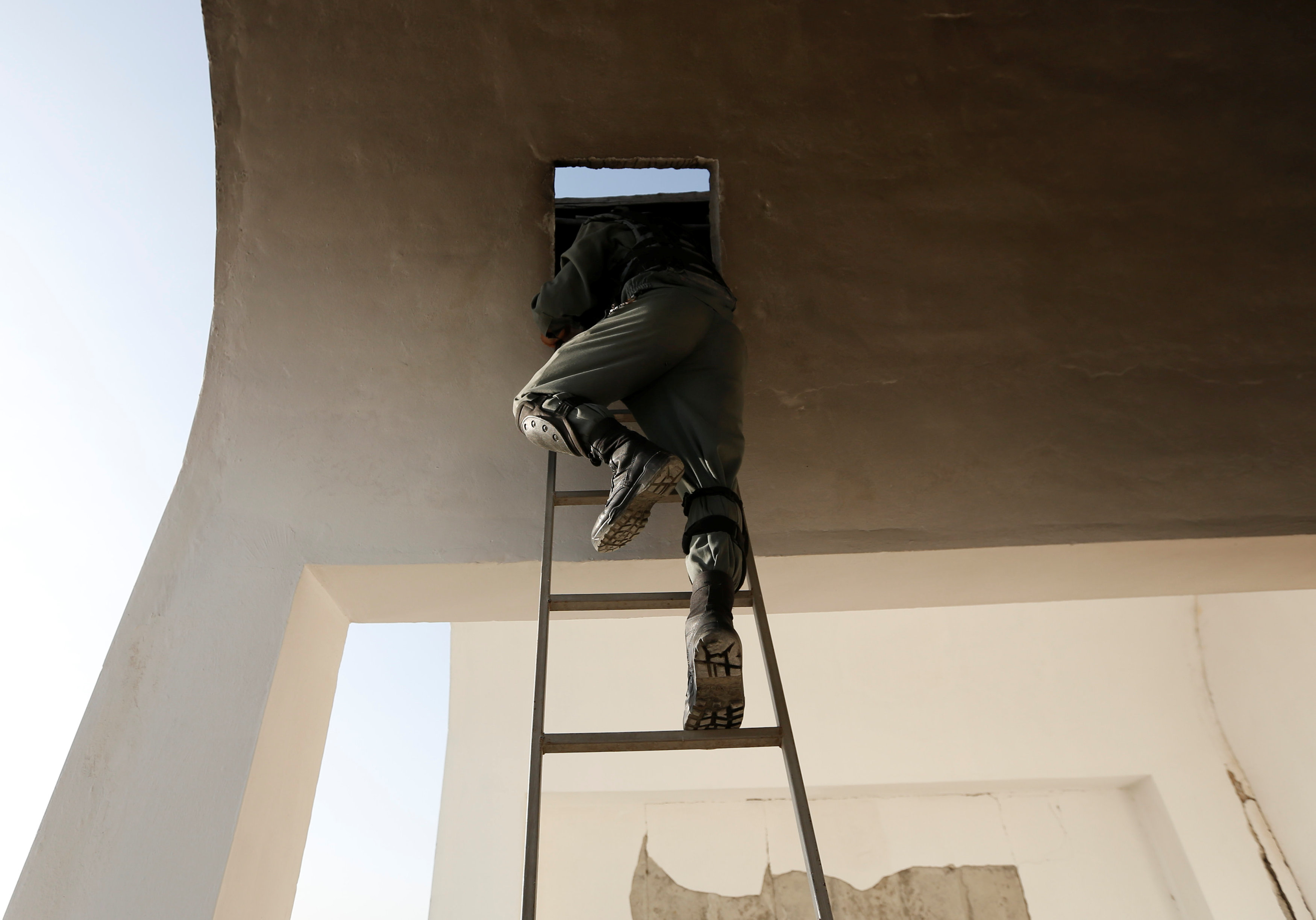 أحد أفراد الشرطة الأفغانية يتسلق سلم للصعود أعلى المسجد