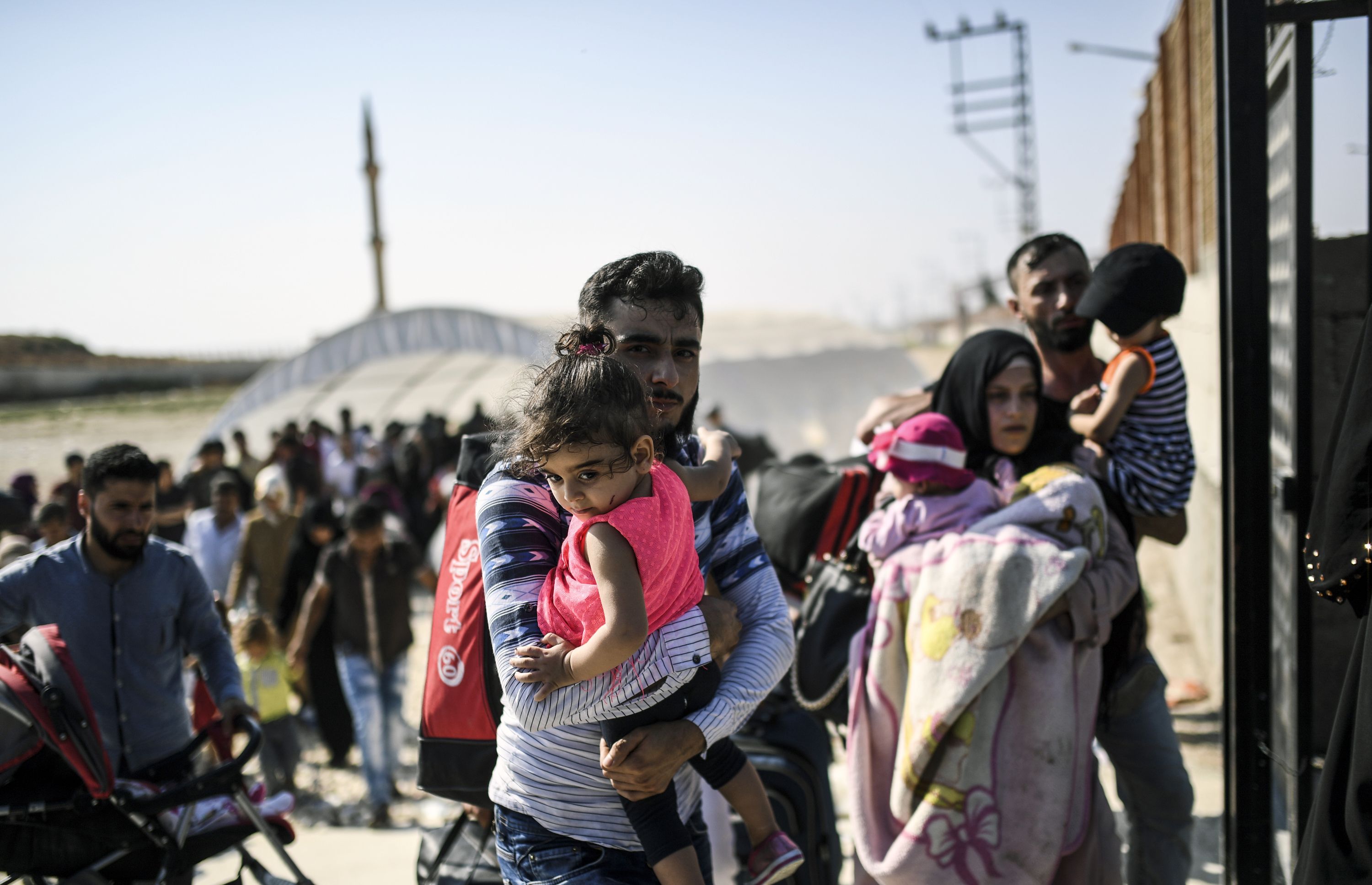 رجل يحمل طفلته أثناء عبور الحدود التركية إلى سوريا