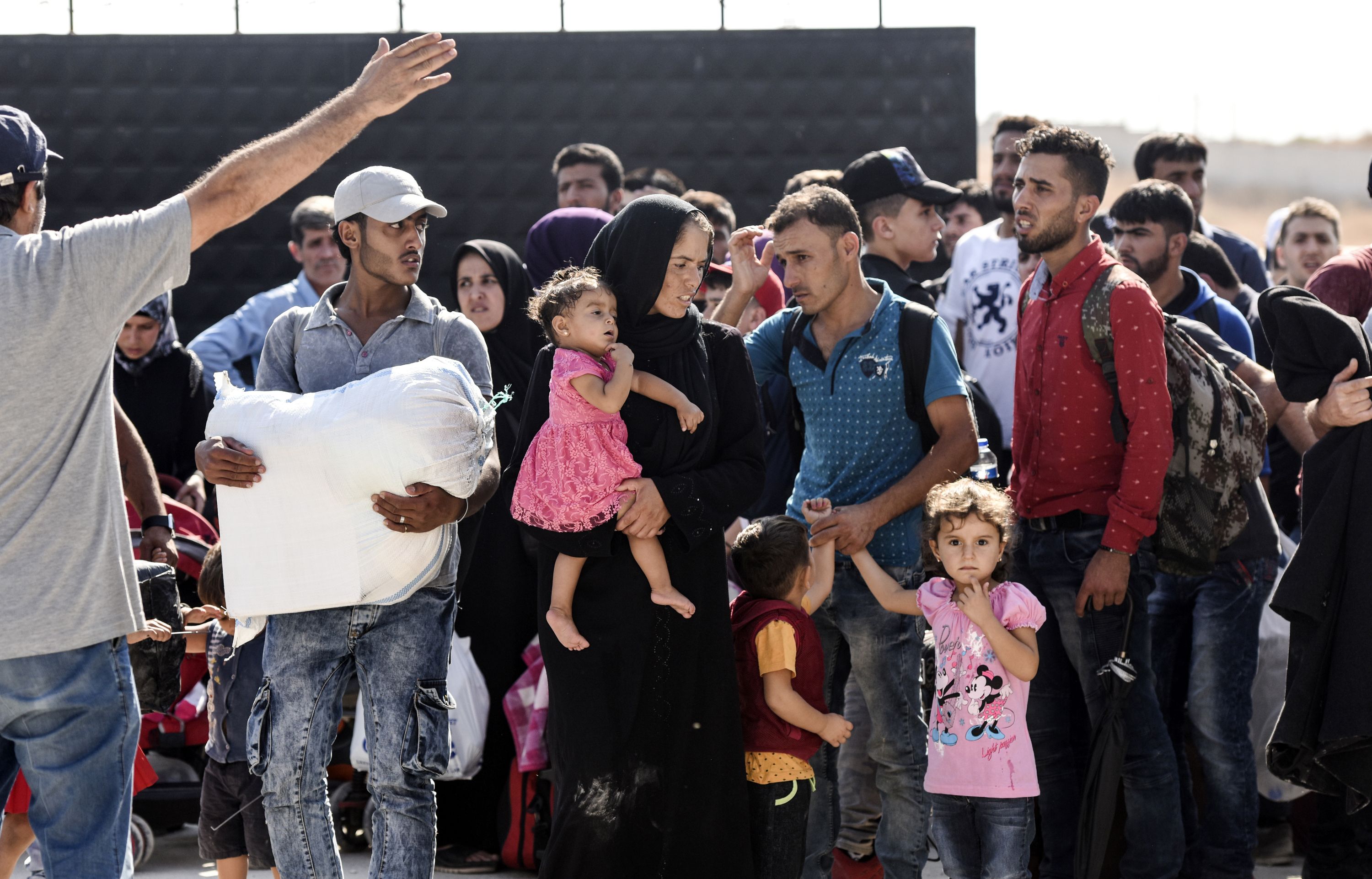 سيدة تحمل طفلتها فى انتظار عبور الحدود التركية