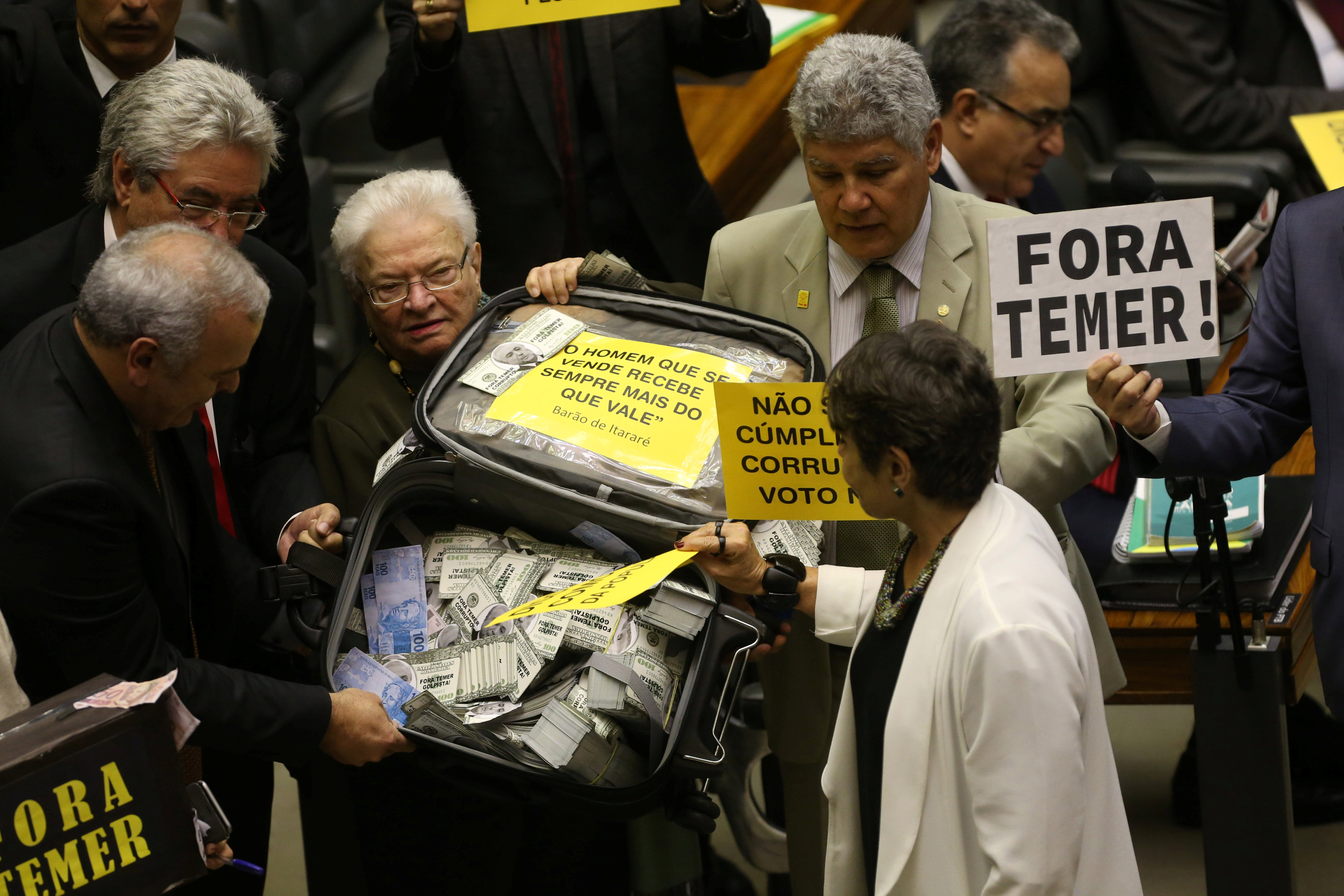 نواب المعارضة البرازيلية يحملون حقيبة بها أموال فى اشارة إلى تلقى الرئيس تامر أموال
