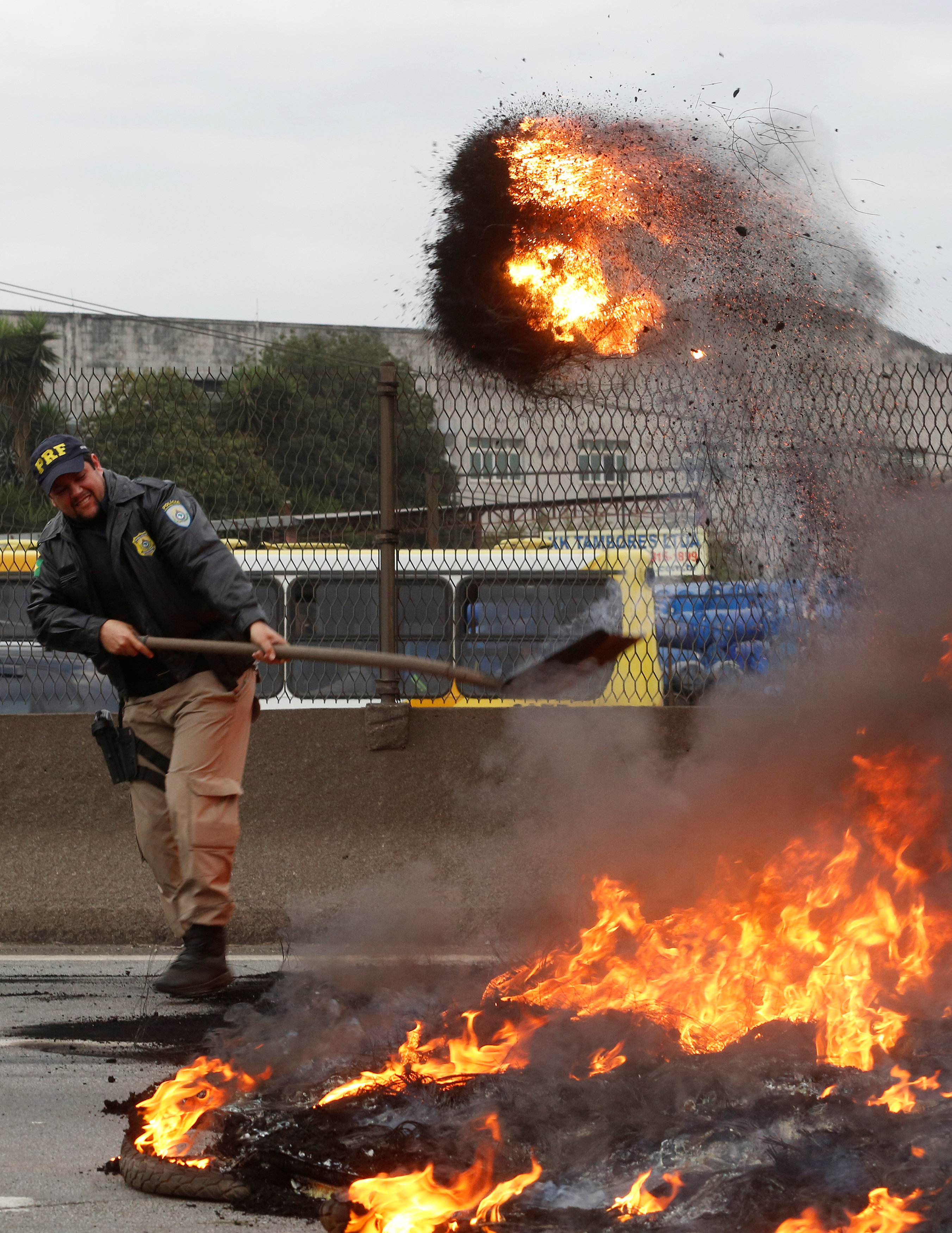 أحد أفراد الشرطة البرازيلية يحاول فتح الطريق وسط اكوام القمامة المشتعلة