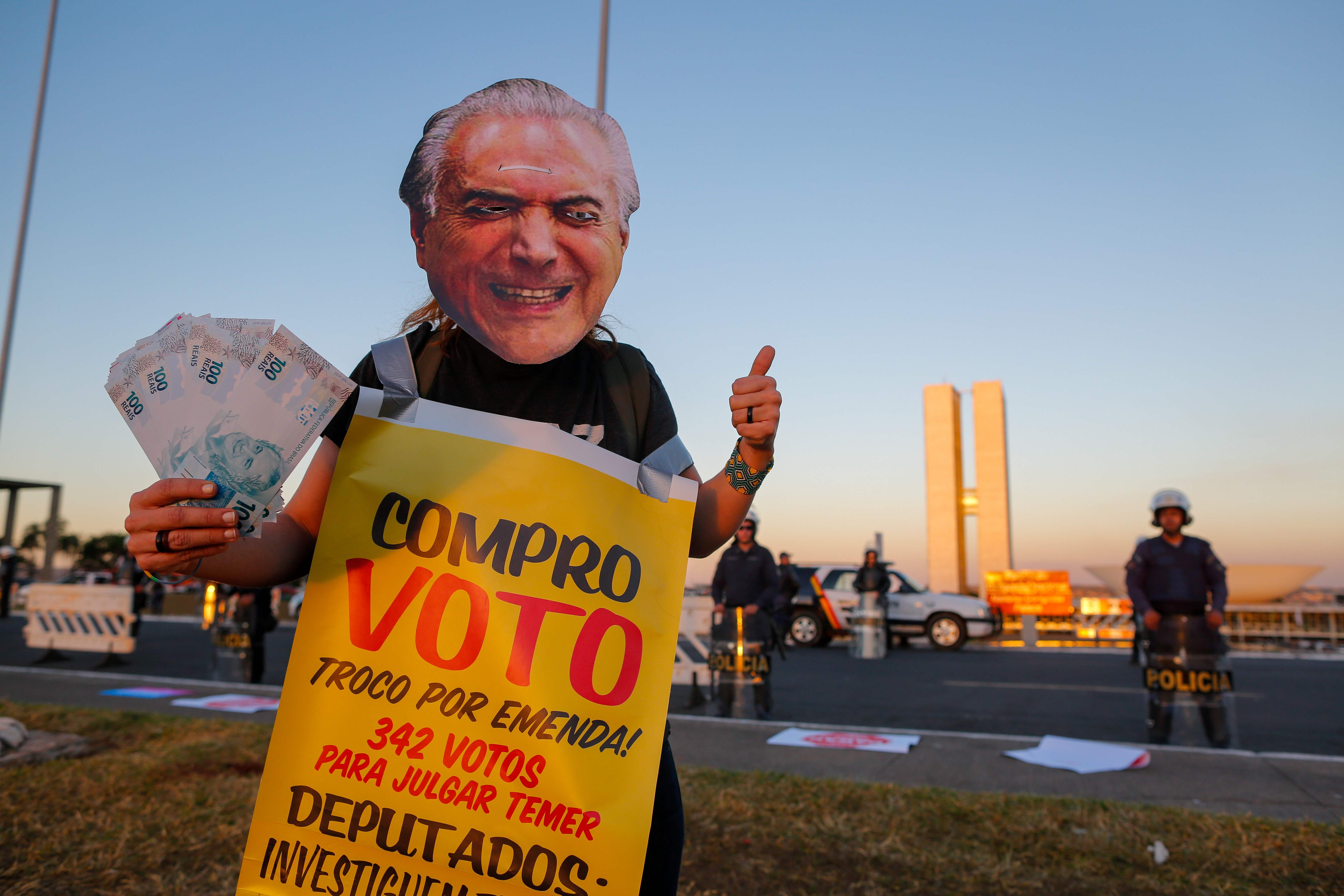شخص يضع قناع لصورة مسيئة للرئيس البرازيلى