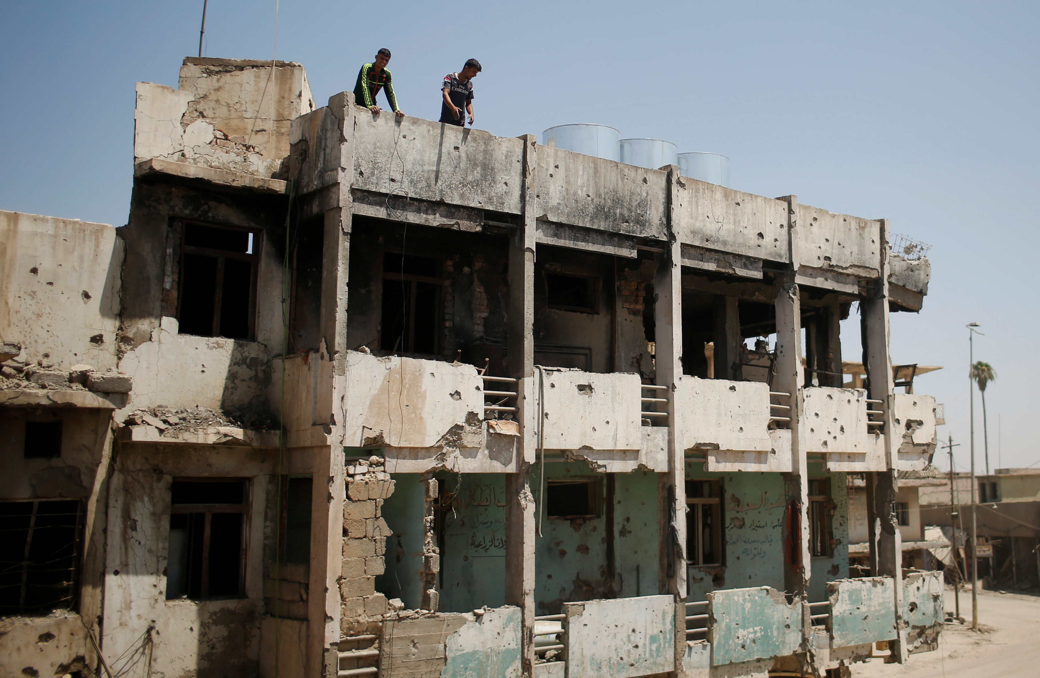 شباب عراقيين أعلى مبنى مدمر إثر الحرب فى الموصل