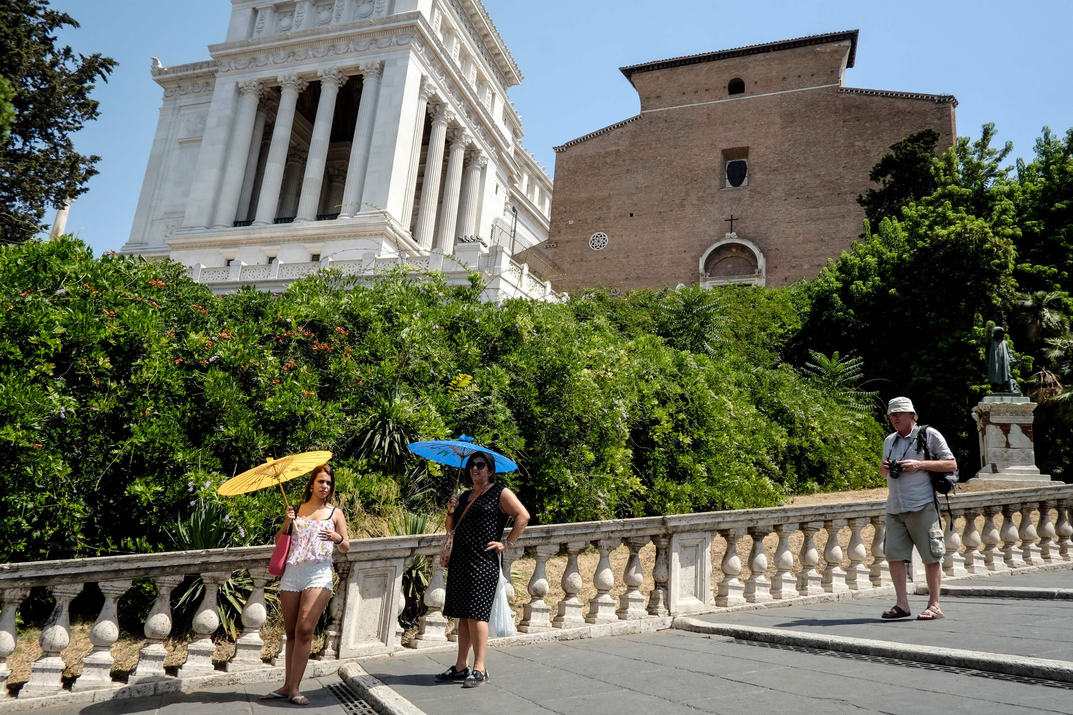 سياح فى إيطاليا يحتمون من أشعة الشمس بالشمسيات