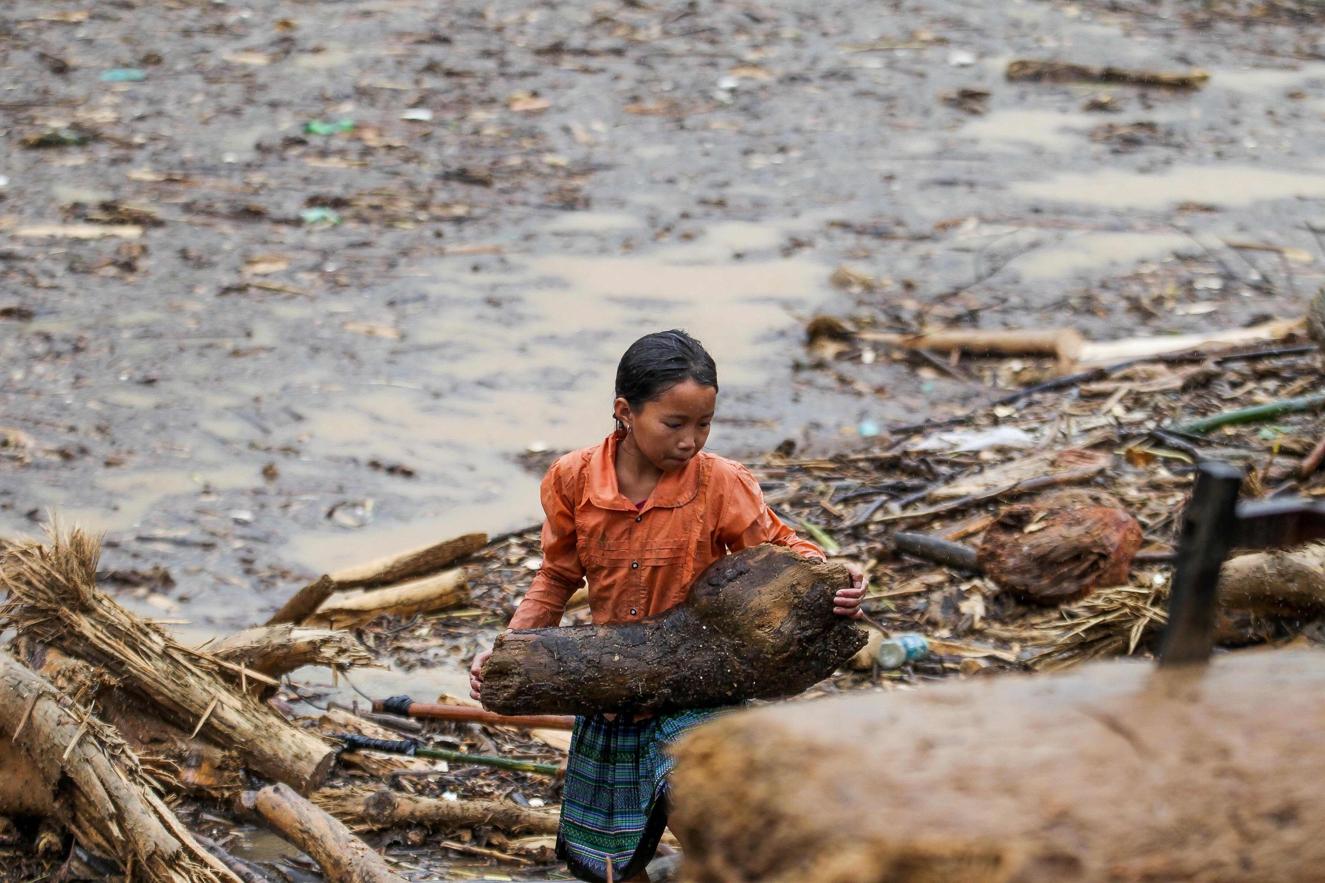 طفلة تحمل أخشاب وسط حطام المنازل فى فيتنام