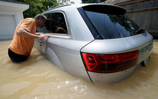 رجل يعاين سيارته التى تعوم وسط مياه الاعصار