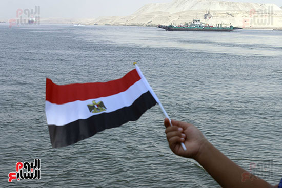 علم مصر يرتفع بقناة السويس وفي الخلفية تظهر المعديات 
