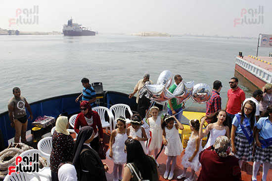 الأطفال يستعدون للاحتفال أمام السفن العابرة بقناة السويس 