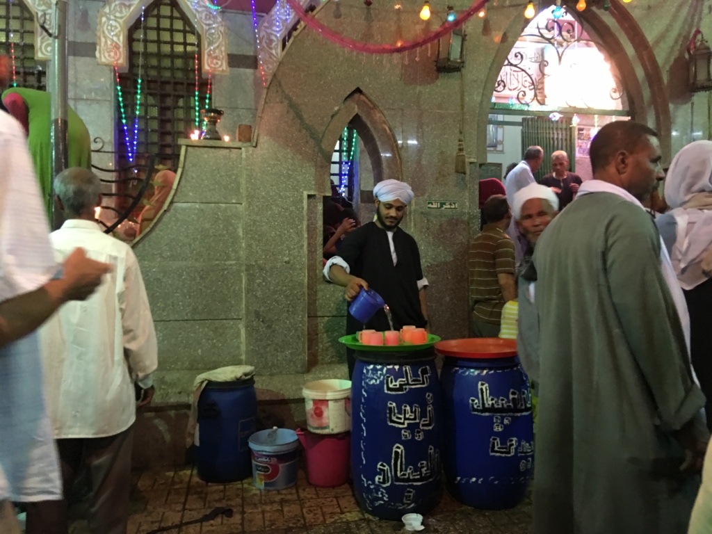 4- أحد المتطوعين يقوم بتقديم المياه لزور الإمام السيوطي