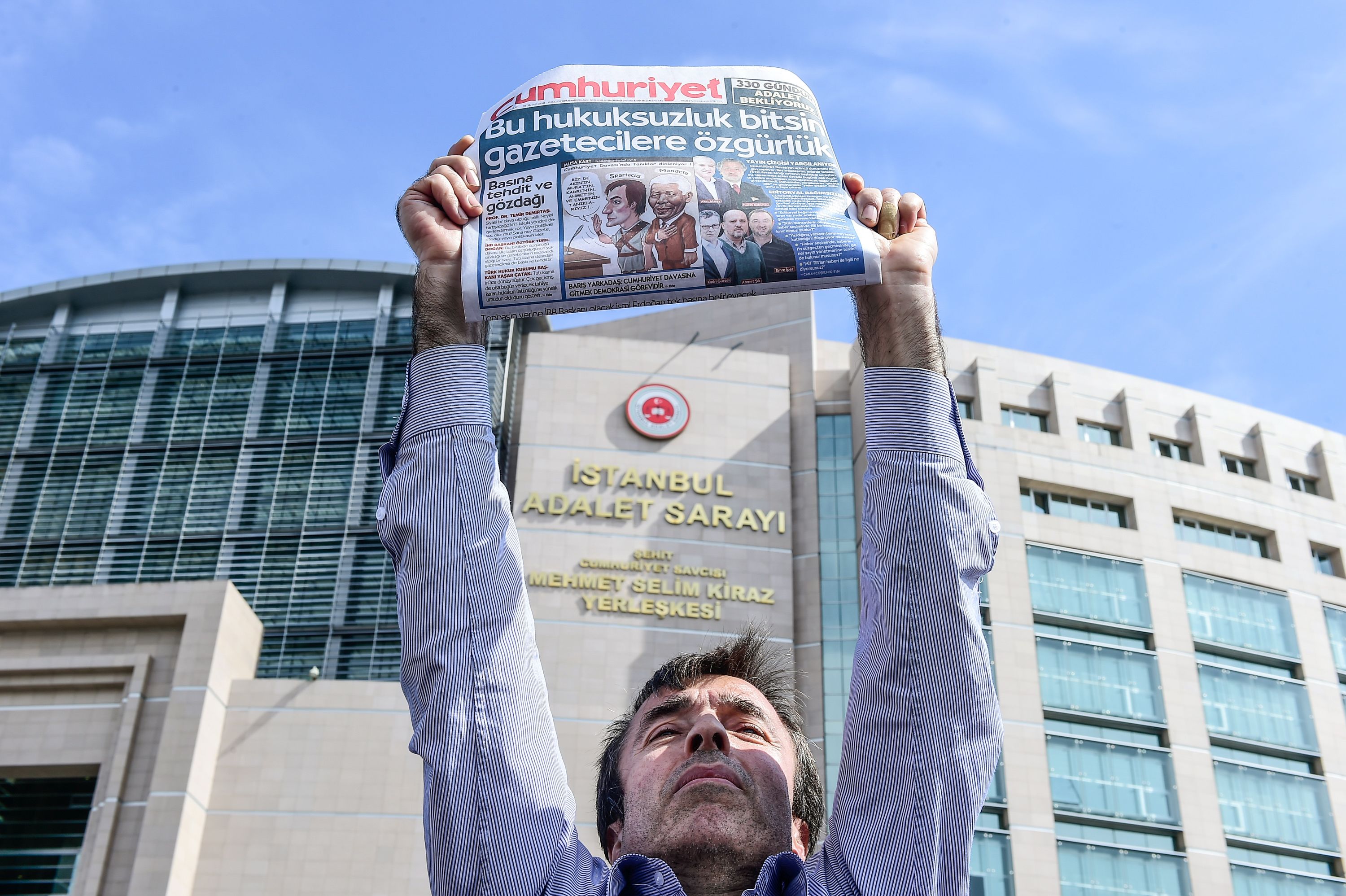 متظاهر أمام محكمة اسطنبول يرفع نسخة من صحيفة جمهوريت