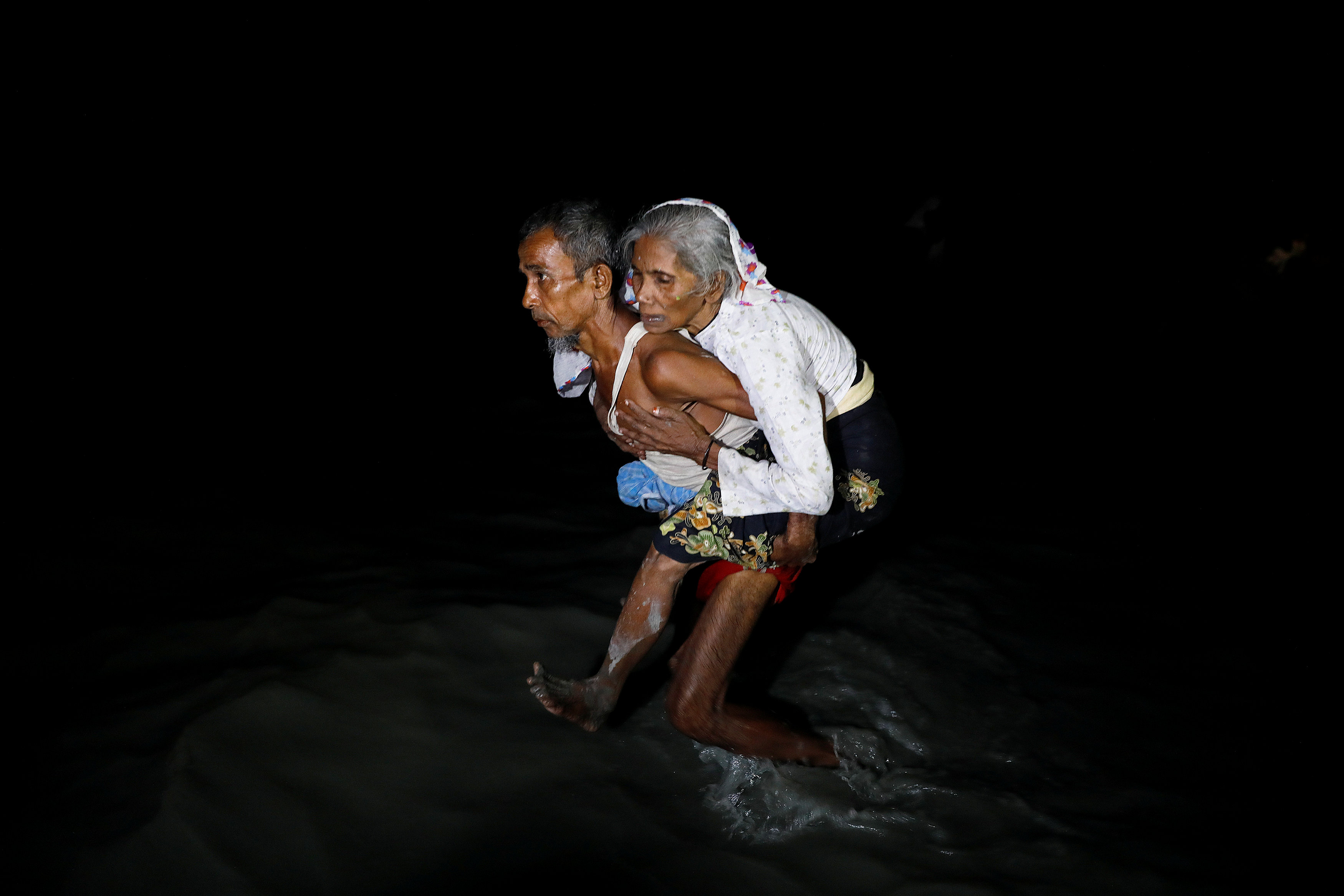 رجل يحمل سيدة عجوز للهرب من ميانمار