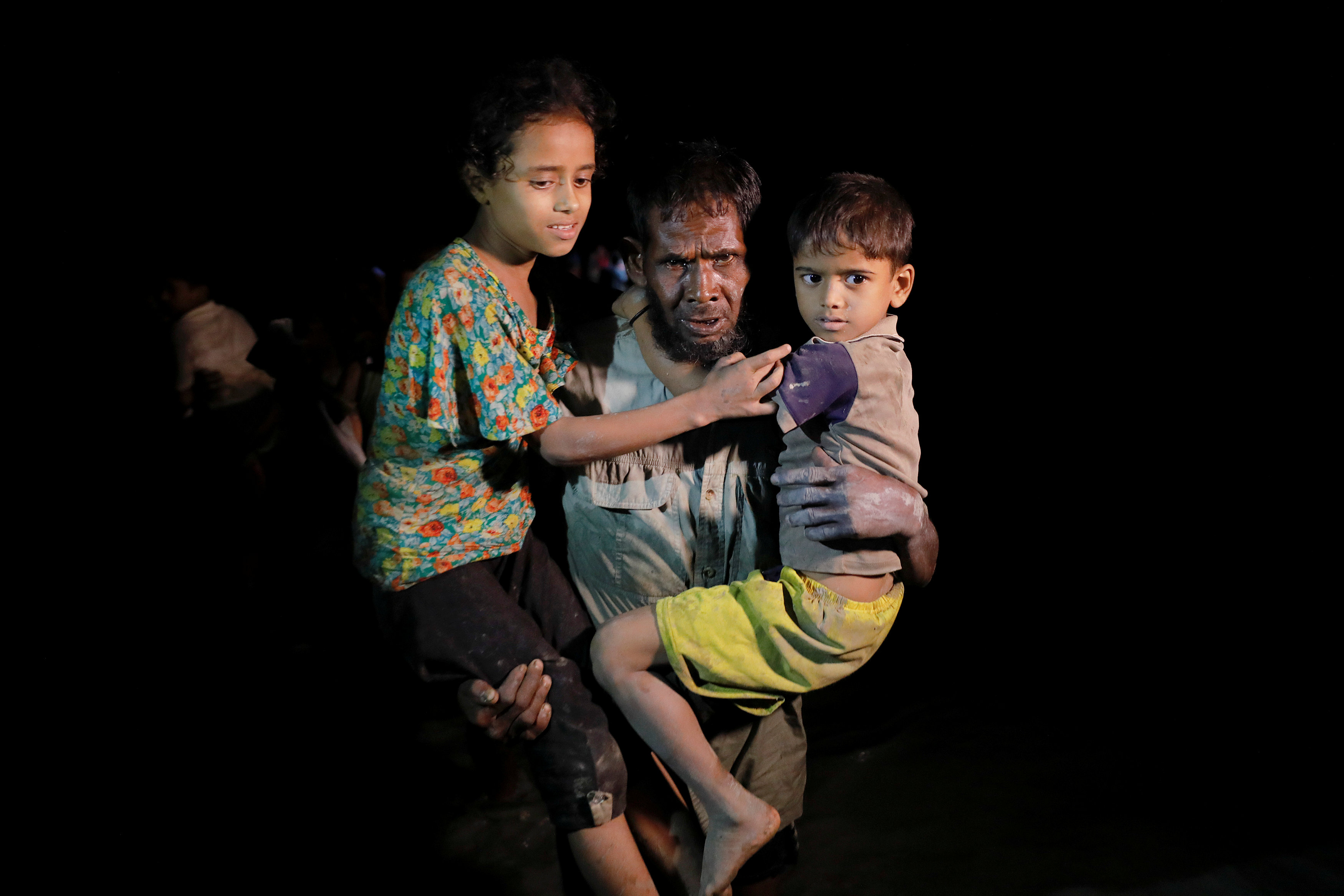 رجل يحمل أطفاله للهرب من ميانمار