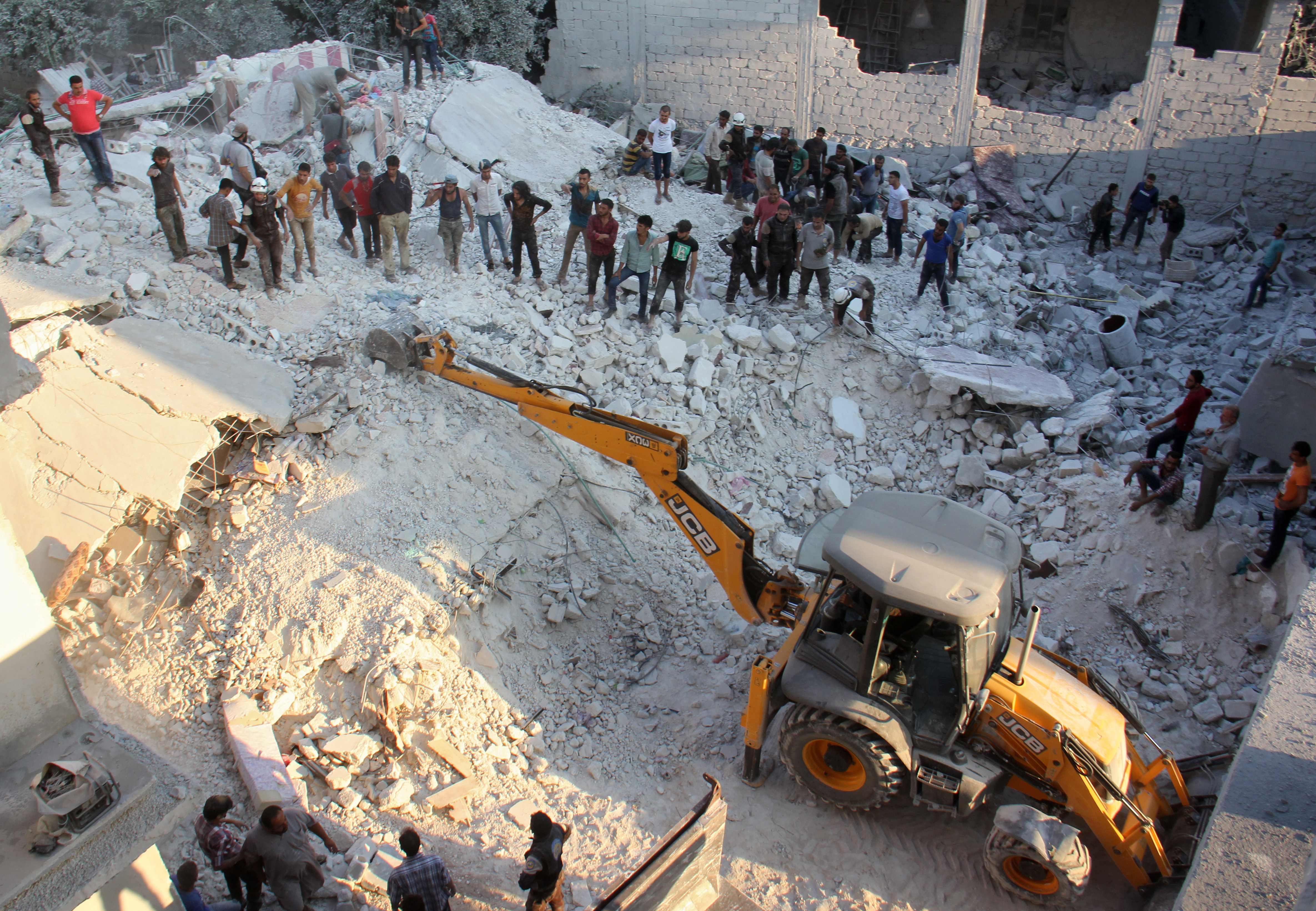 معدات ثقيلة لإزالة أنقاض منازل منهارة إثر قصف جوى بإدلب