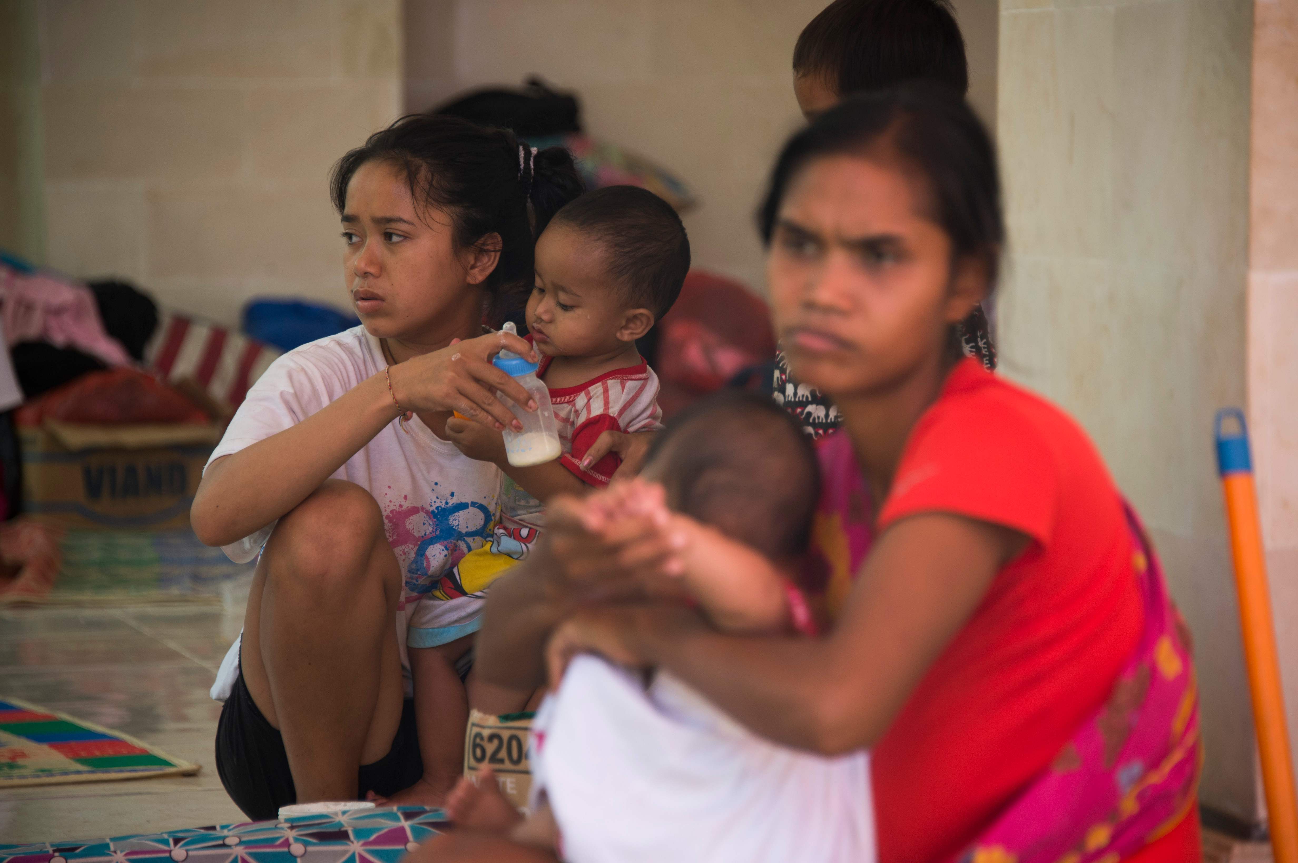 طفلة تطعم أخيها الصغير بمركز الإيواء فى إندونيسيا