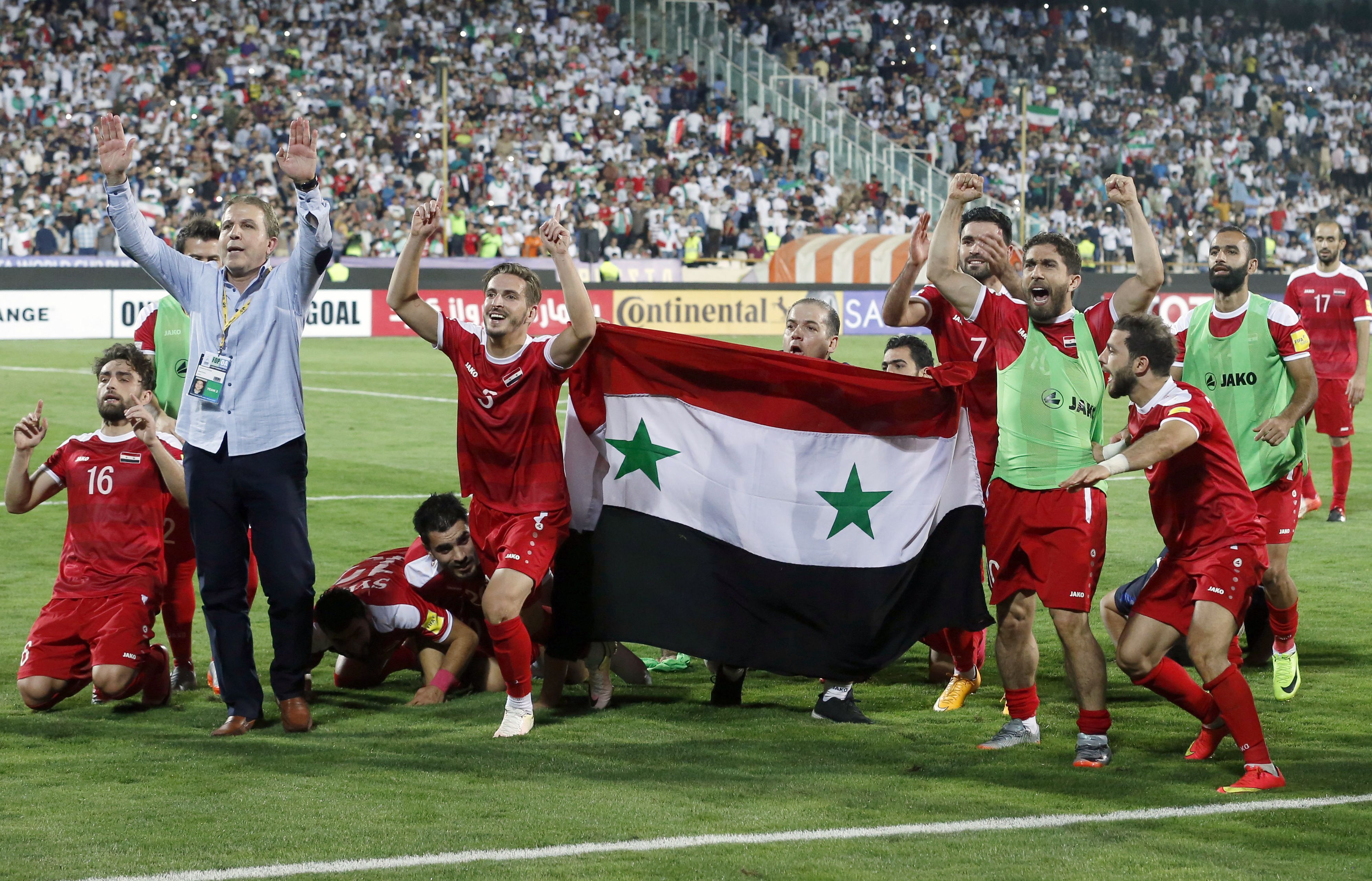 لاعبو سوريا يحملون علم البلاد احتفالاً بالتأهل للملحق