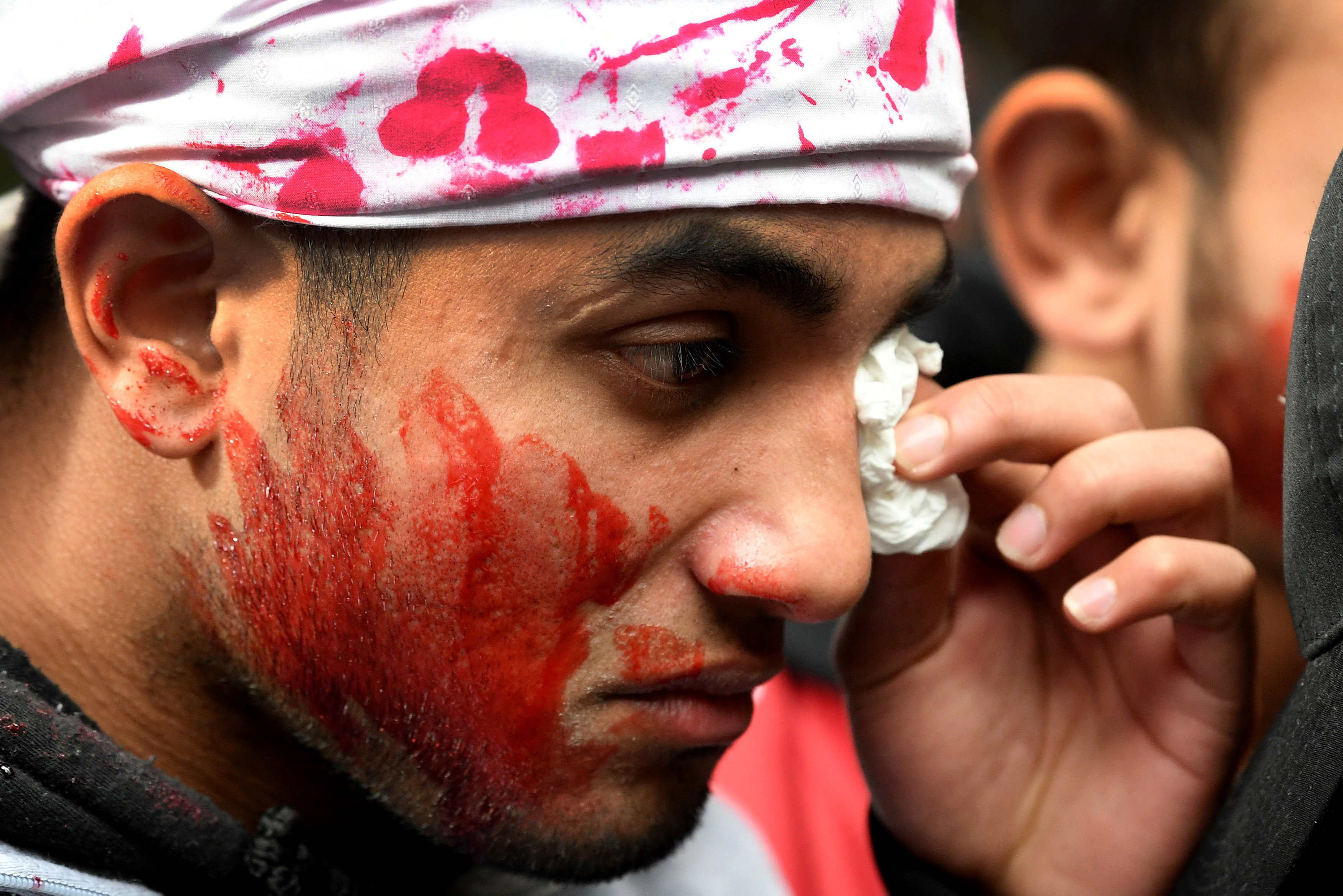 شخص يبكى وقد لطخ وجهه باللون الأحمر حزنا على عمليات الابادة لمسلمى بورما