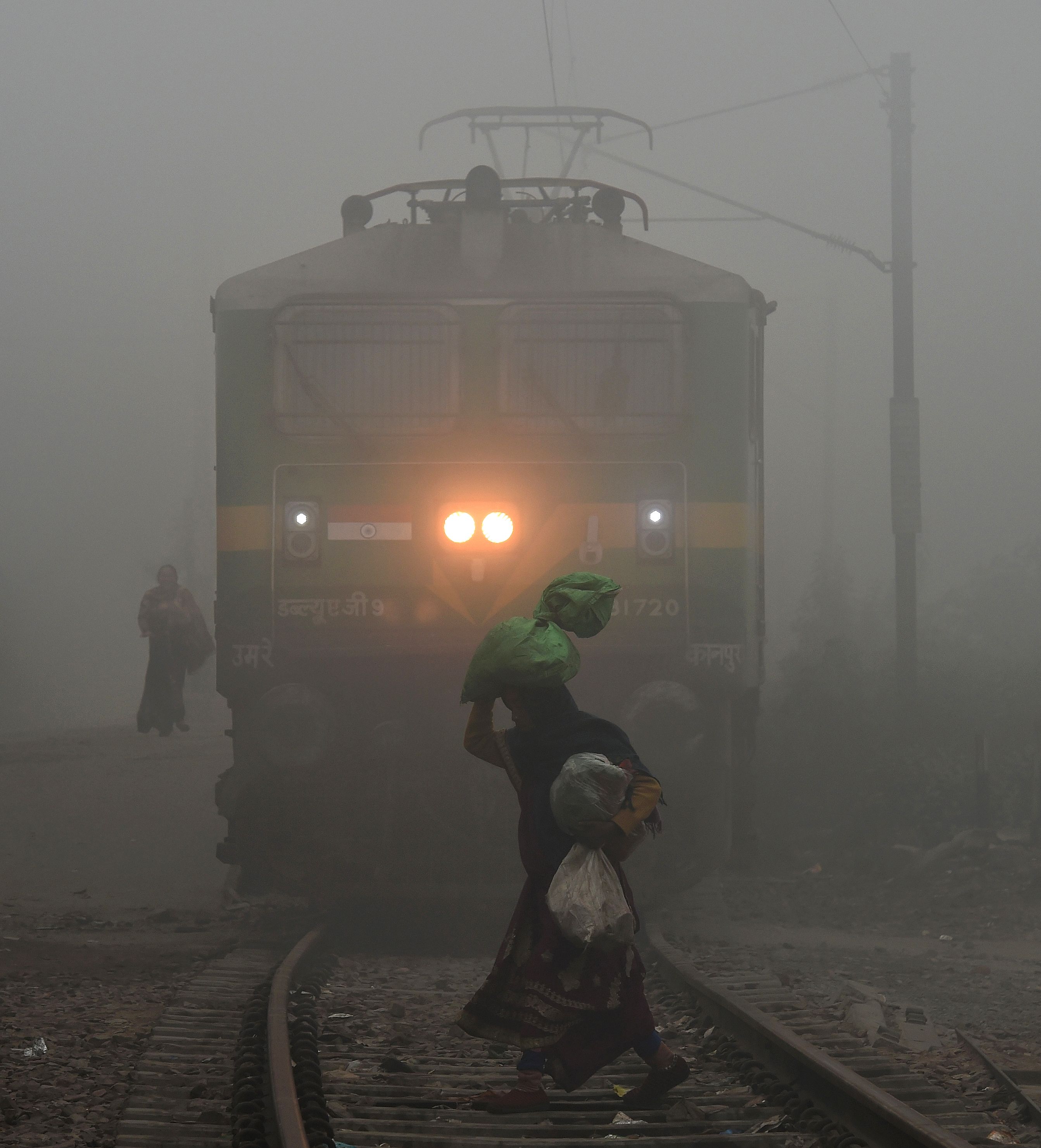 سيدة تمر أمام قطار وسط الضباب الدخانى بالهند