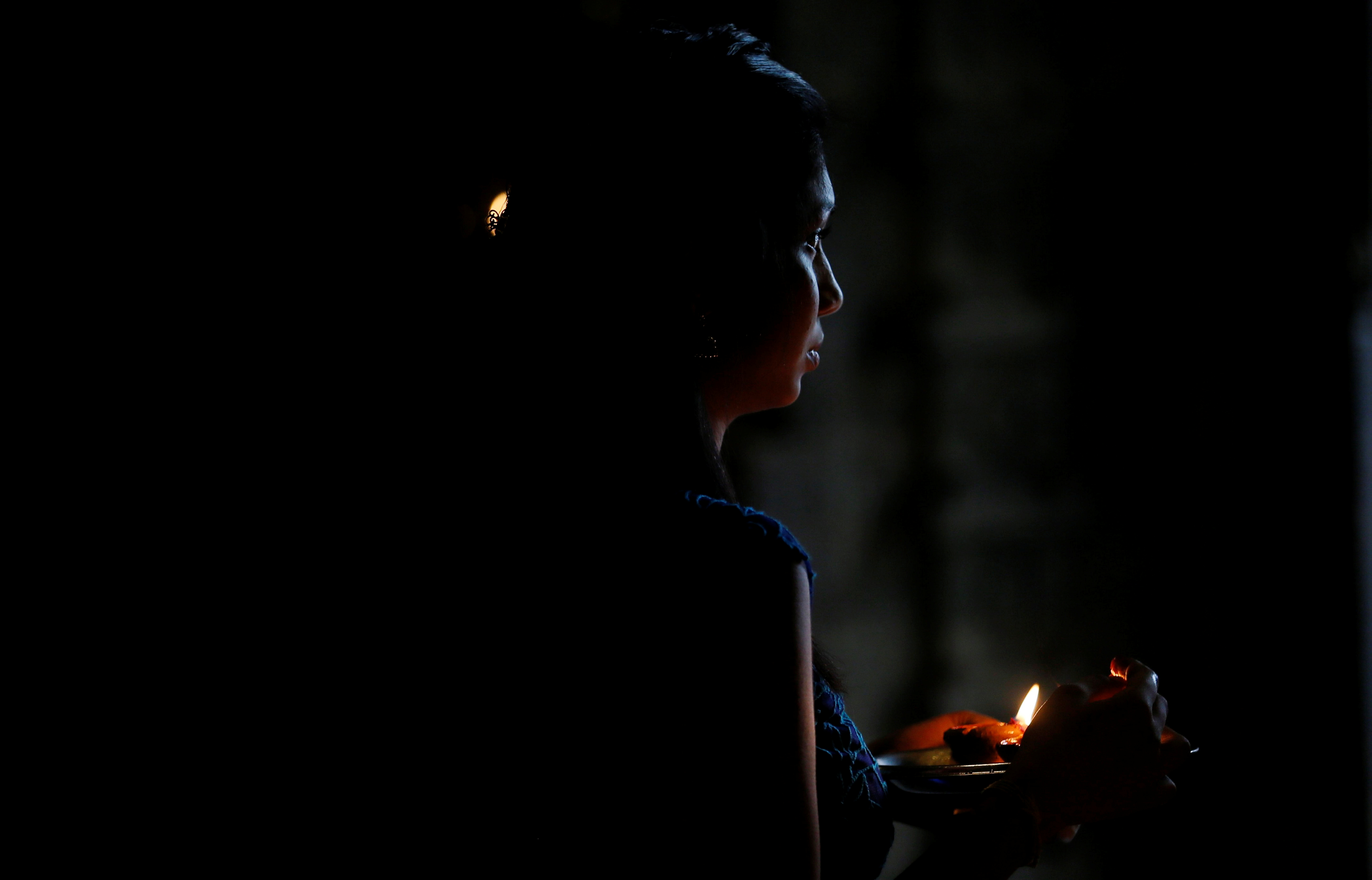 سيدة تشعل شمعة خلال الاحتفالات الدينية بالبونجال
