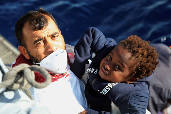 منقذ يحمل طفل ضمن المهاجرين غير الشرعيين