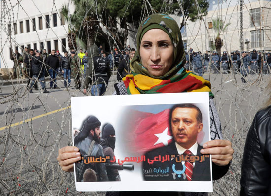 أحد المتظاهرات تحمل صورة أردوغان بشعار الإرهابى