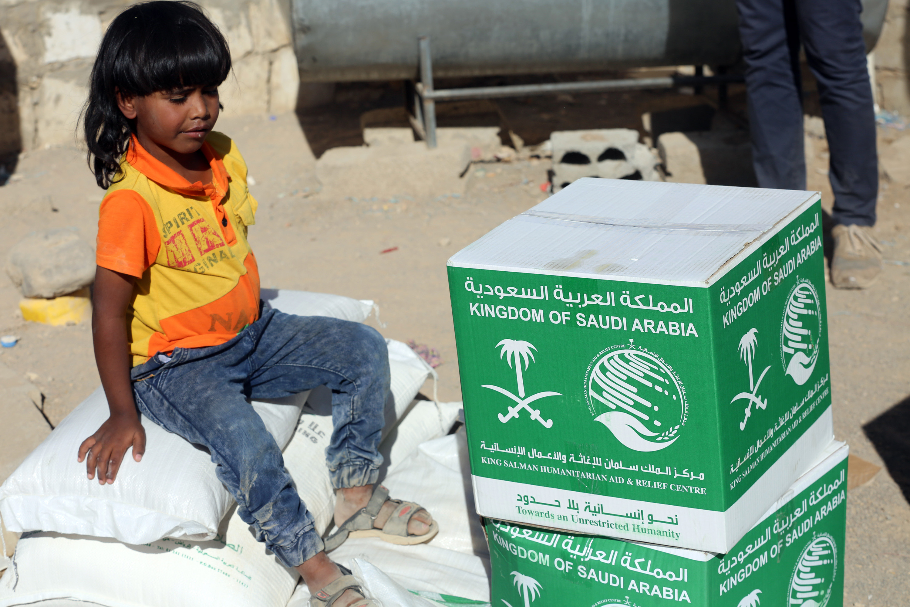 طفل يمنى يجلس بعد تلقى المساعدات السعودية