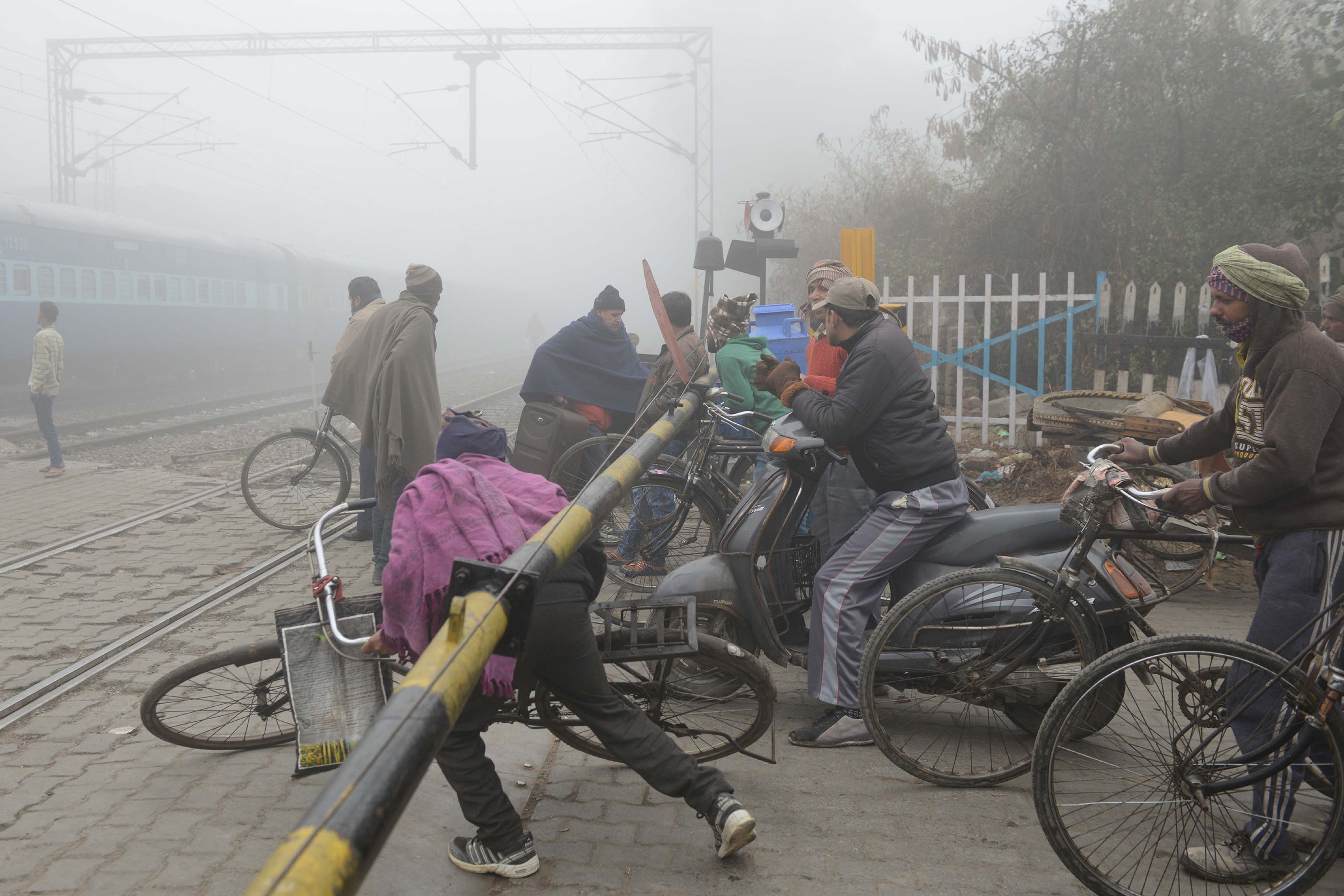 هنود يعبرون خط السك الحديدية أثناء موجة الضباب الدخانى فى الهند