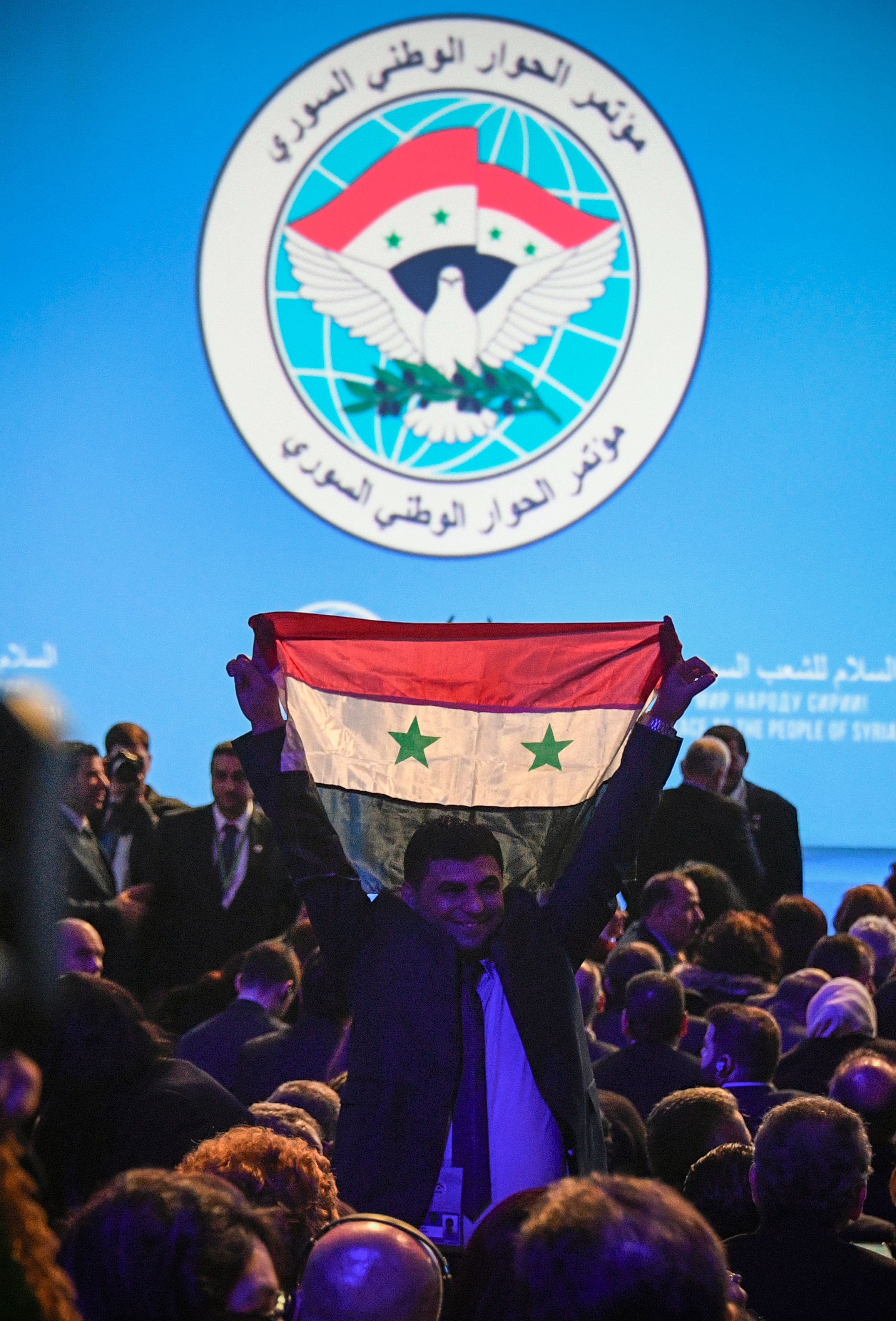 أحد المشاركين فى مؤتمر سوتشى يرفع العلم السورى