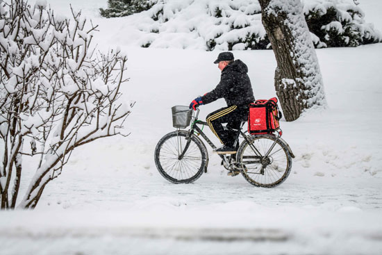 مواطن-يقود-دراجته-وسط-الثلوج