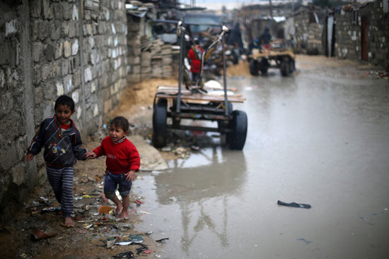 أطفال يعبرون وسط تجمعات مياه الأمطار فى غزة