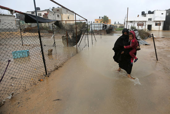 سيدة فلسطينية تسير وسط تجمعات مياه الأمطار