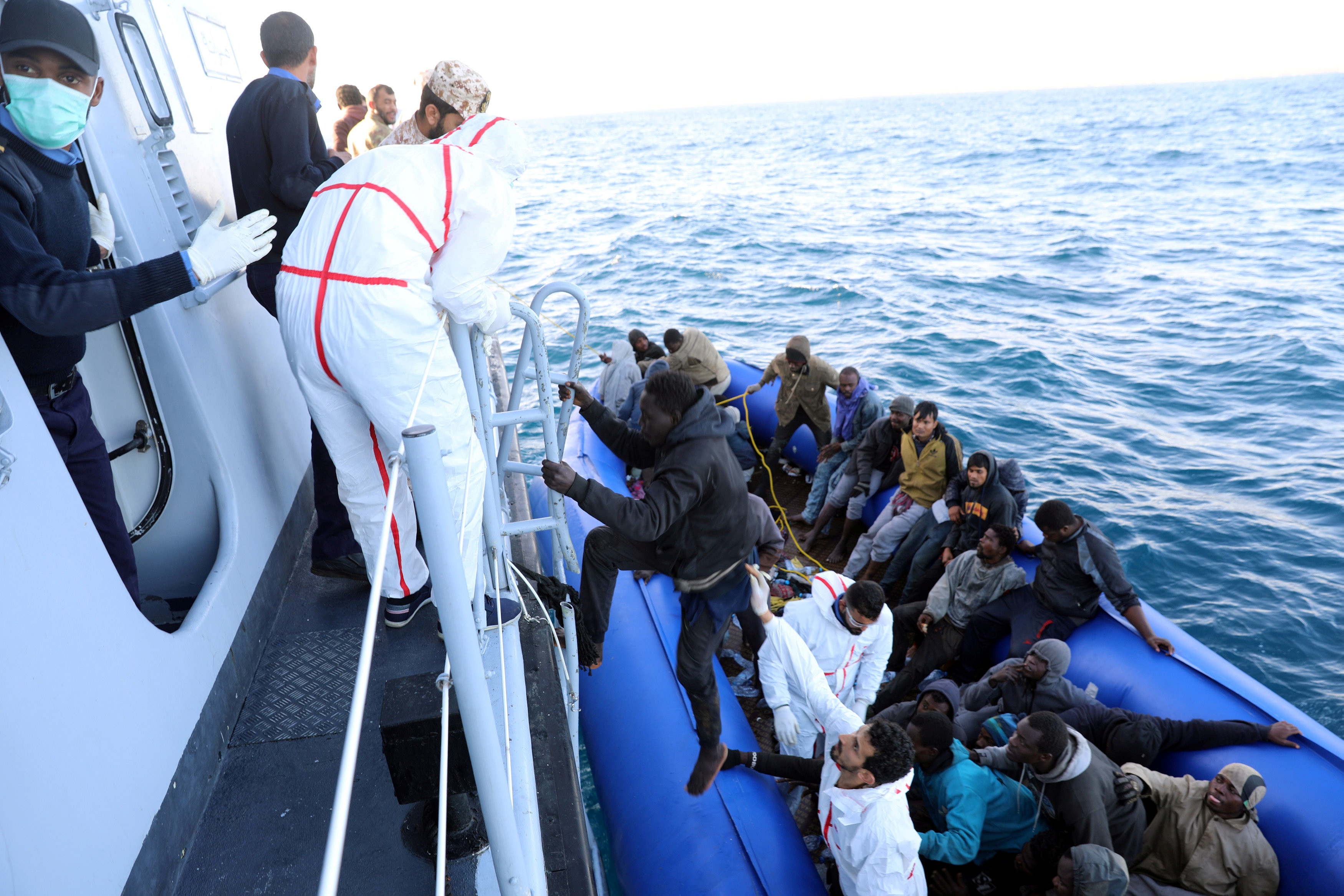أحد المهاجرين يتسلق سفينة الانقاذ الليبية