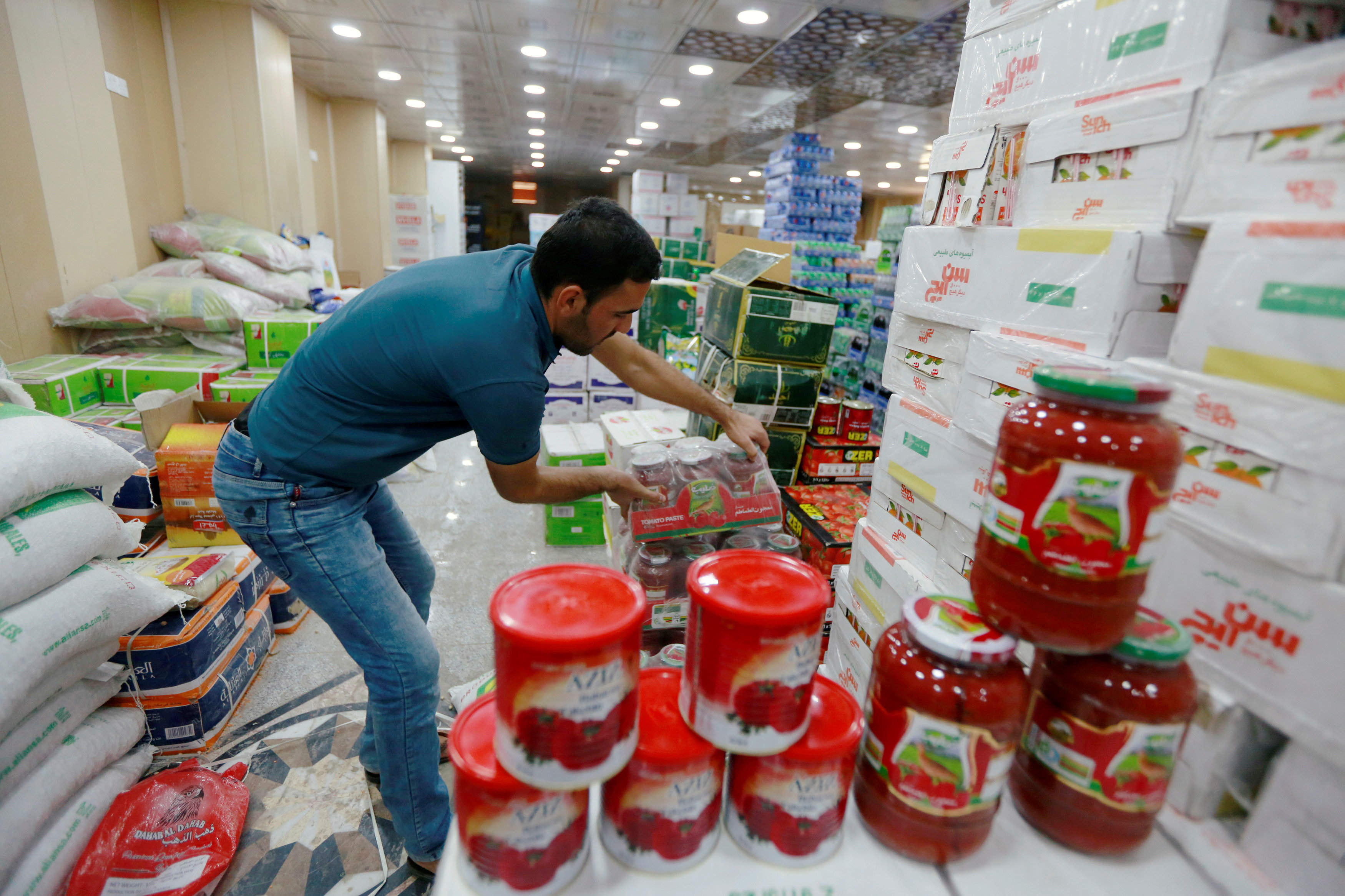 أحد العمال تقوم بترتيب منتجات الطماطم الإيرانية