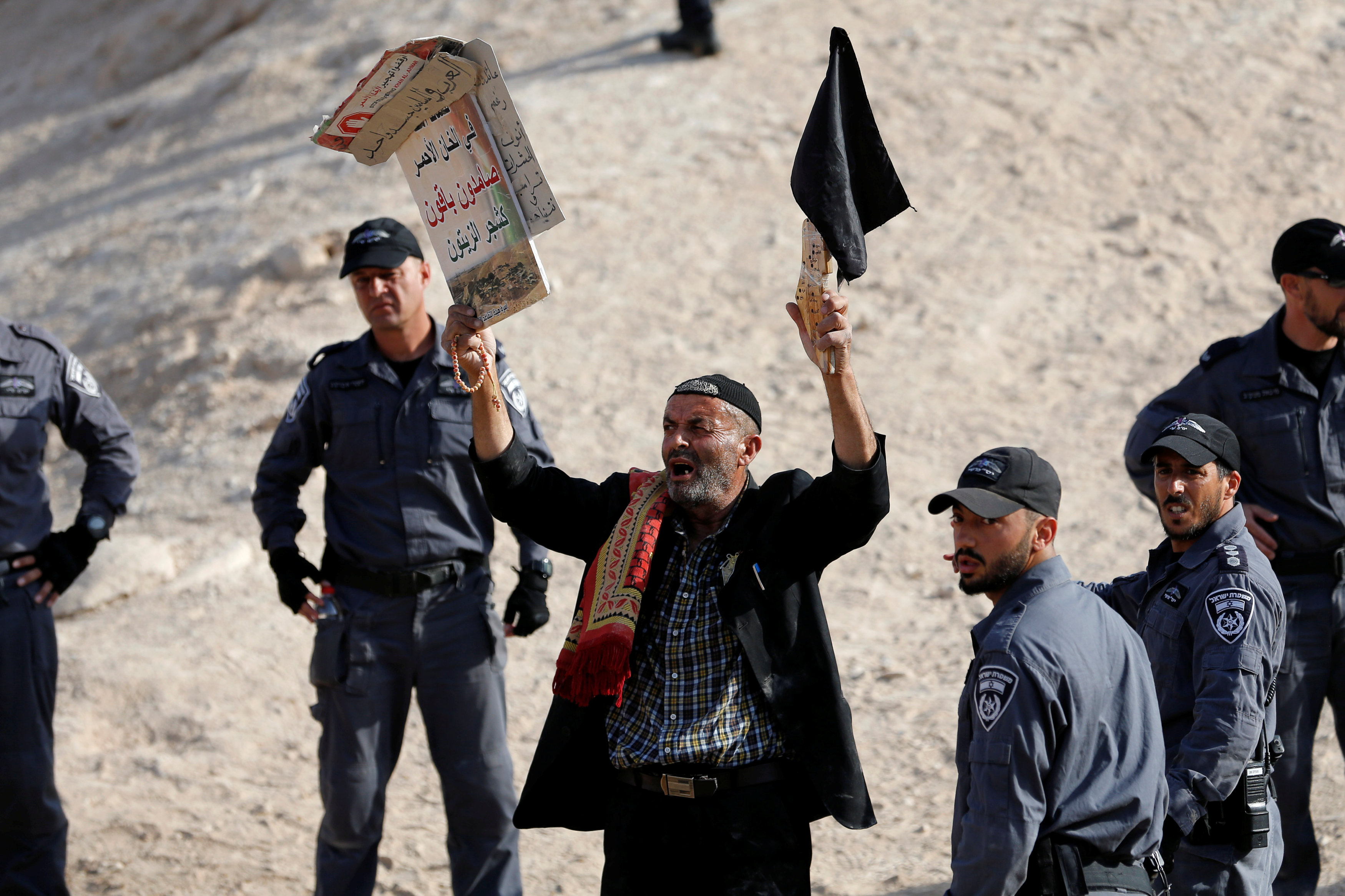 فلسطينى تحاصره قوات الاحتلال بينما يرفع لافتة تدعو للصمود