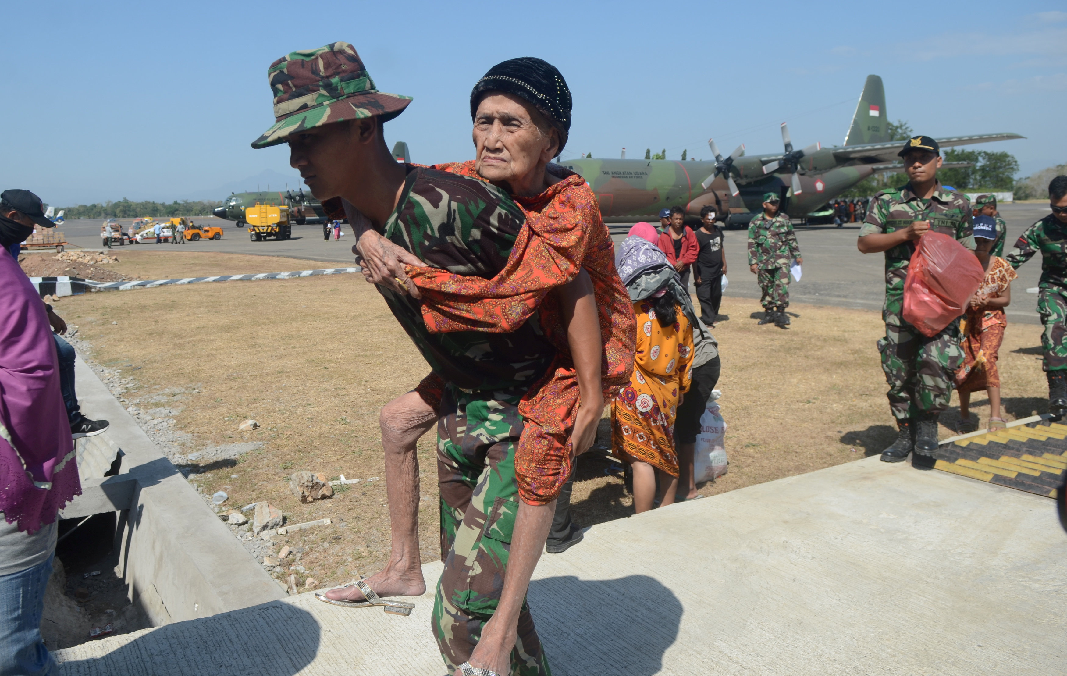 جندى إندونيسى يحمل سيدة عجوز بمناطق الزلزال