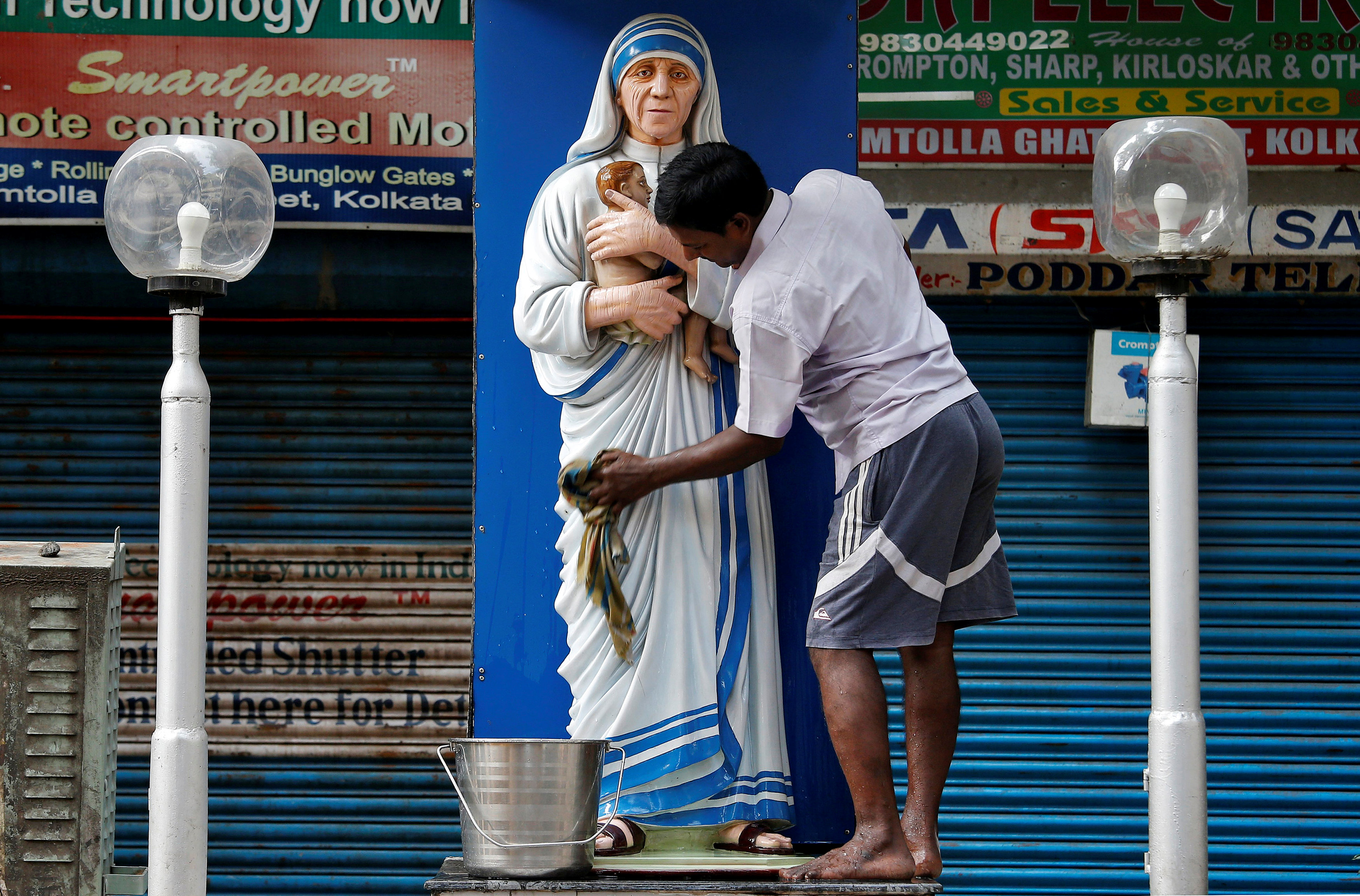 أحد الهنود ينظف تمثال سانت تريز استعدادا للاحتفال بغاندى