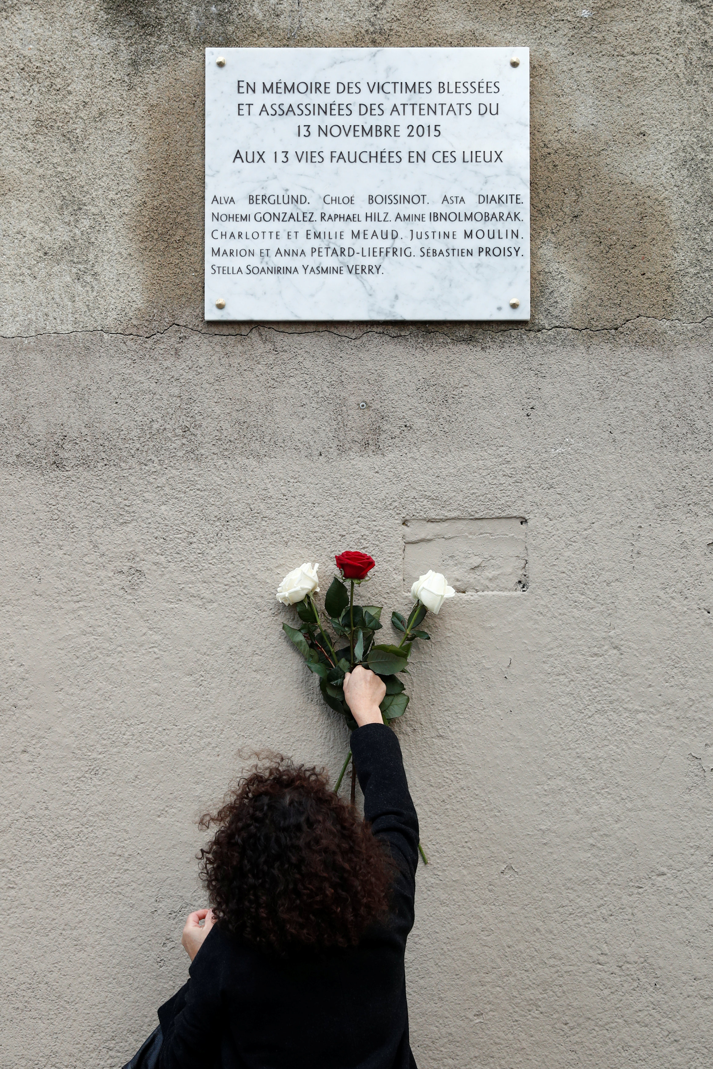 سيدة من أقارب الضحايا تضع حزمة من الزهور على النصب التذكارى