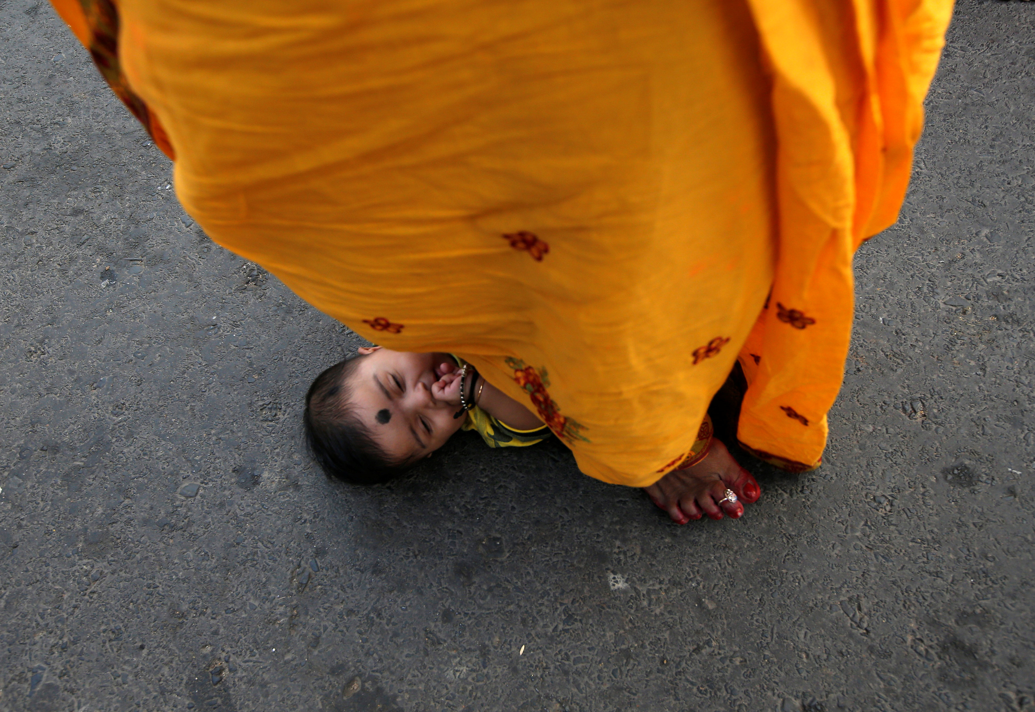 امرأة هندية تقف فوق طفل رضيع طلبا للبركة فى أحد طقوس العيد