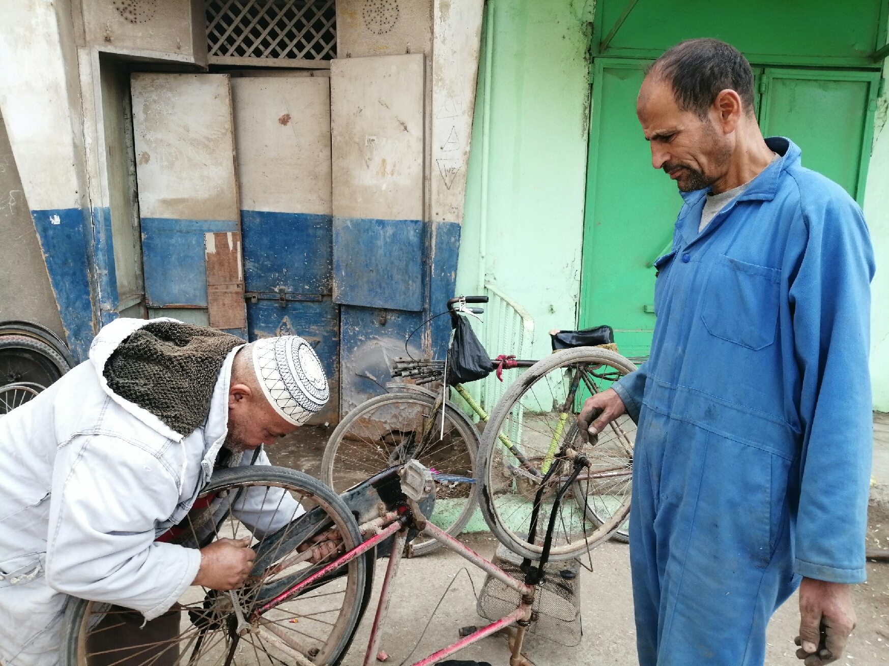 محمد حسن يصلح دراجة وبجواره مالكها