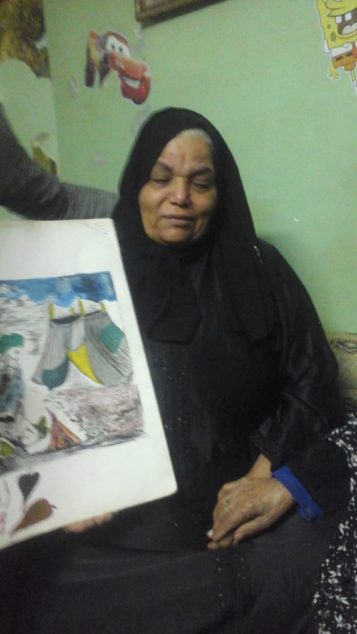 والدة الضحية تحمل إحدى لوحاته