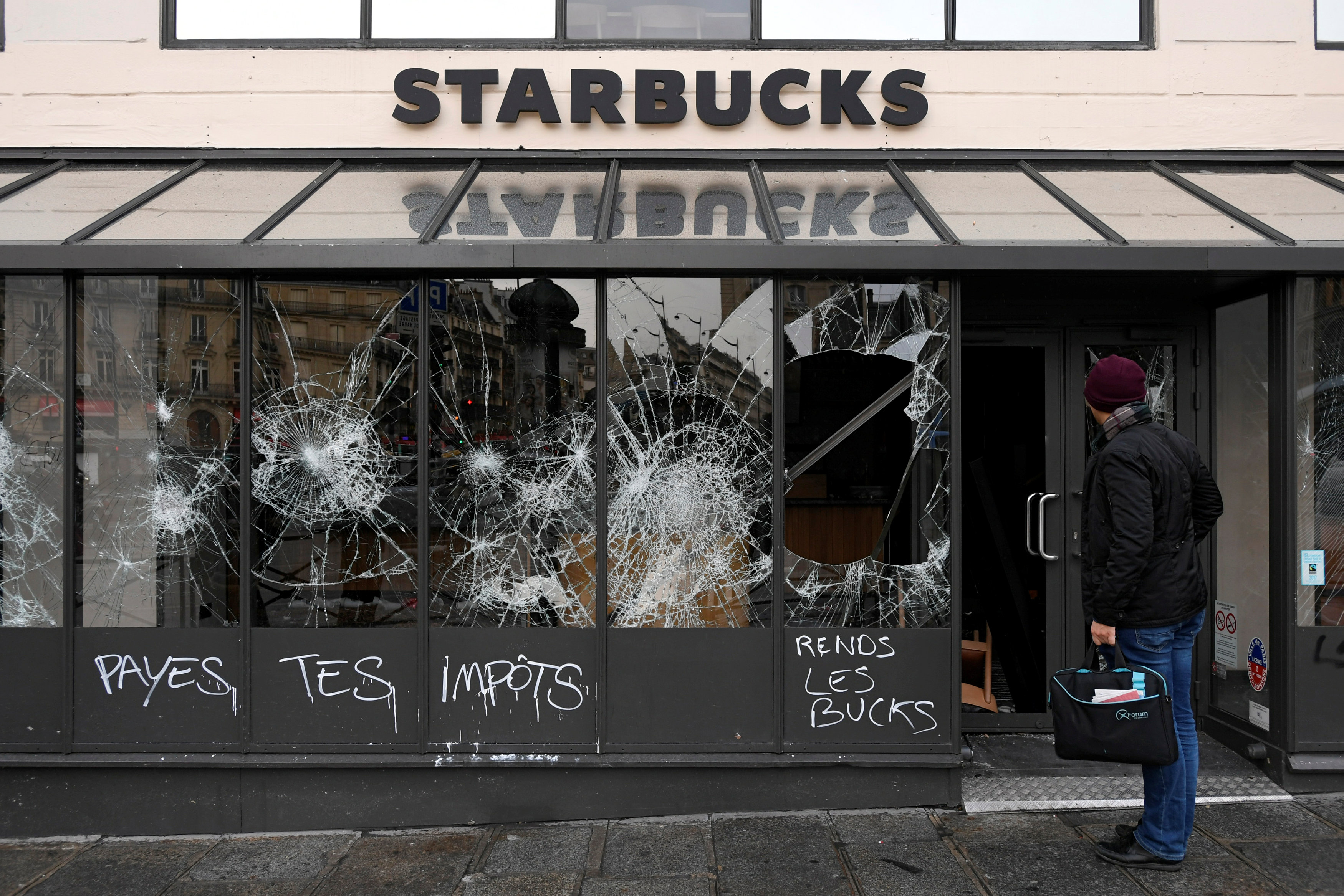 مواطن ينظر لواجهة مقهى دمرتها التظاهرات