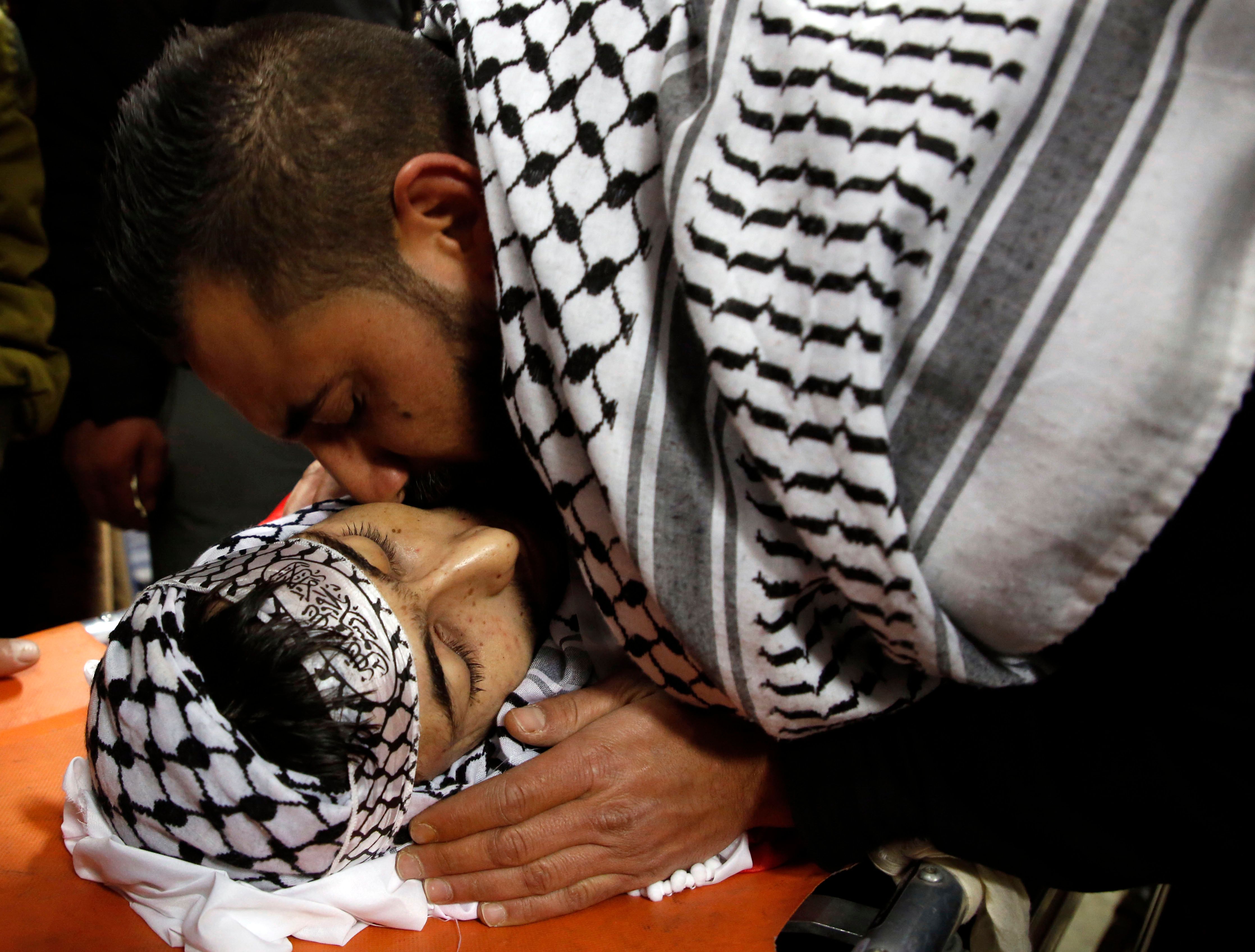 شقيق الشهيد حمزة زمارة يقبله قبل تشييع جثمانه