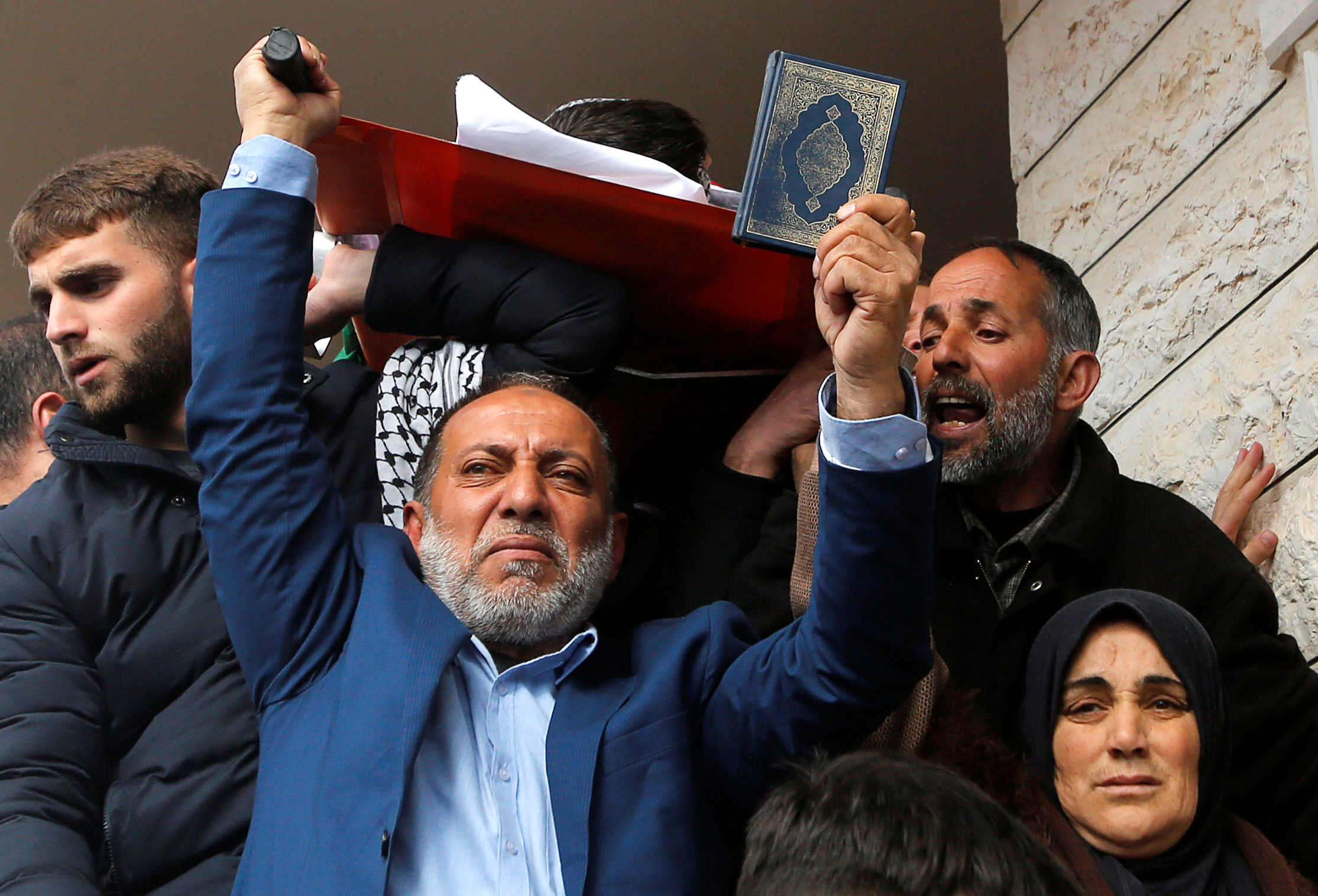 فلسطينى يرفع المصحف أمام جثمان الشاب الشهيد